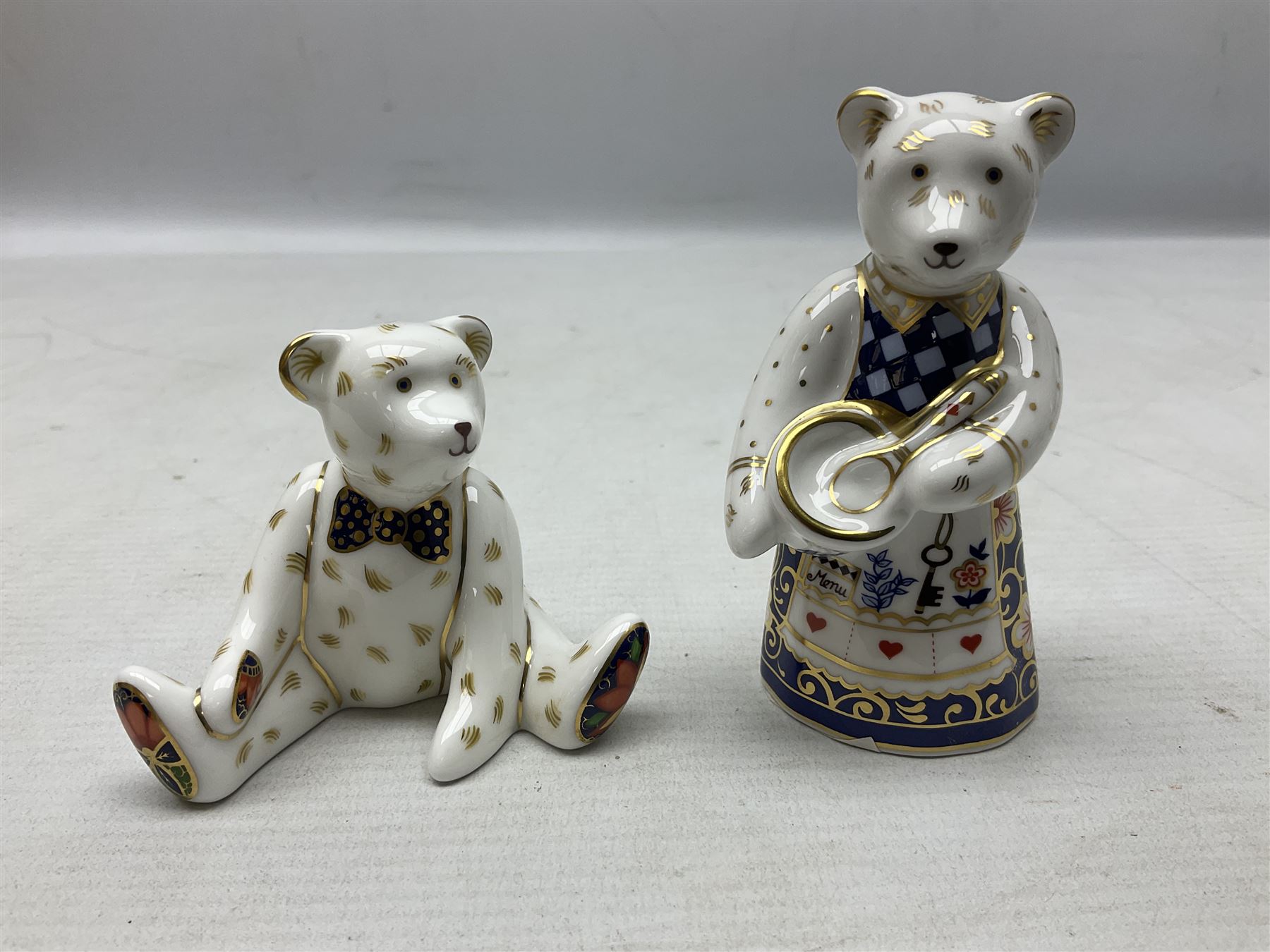 Four Royal Crown Derby teddy paperweights, comprising Teddy Cook, two Teddy George and Seated Teddy, all without stoppers, together with Crown Namestake with gold stopper 