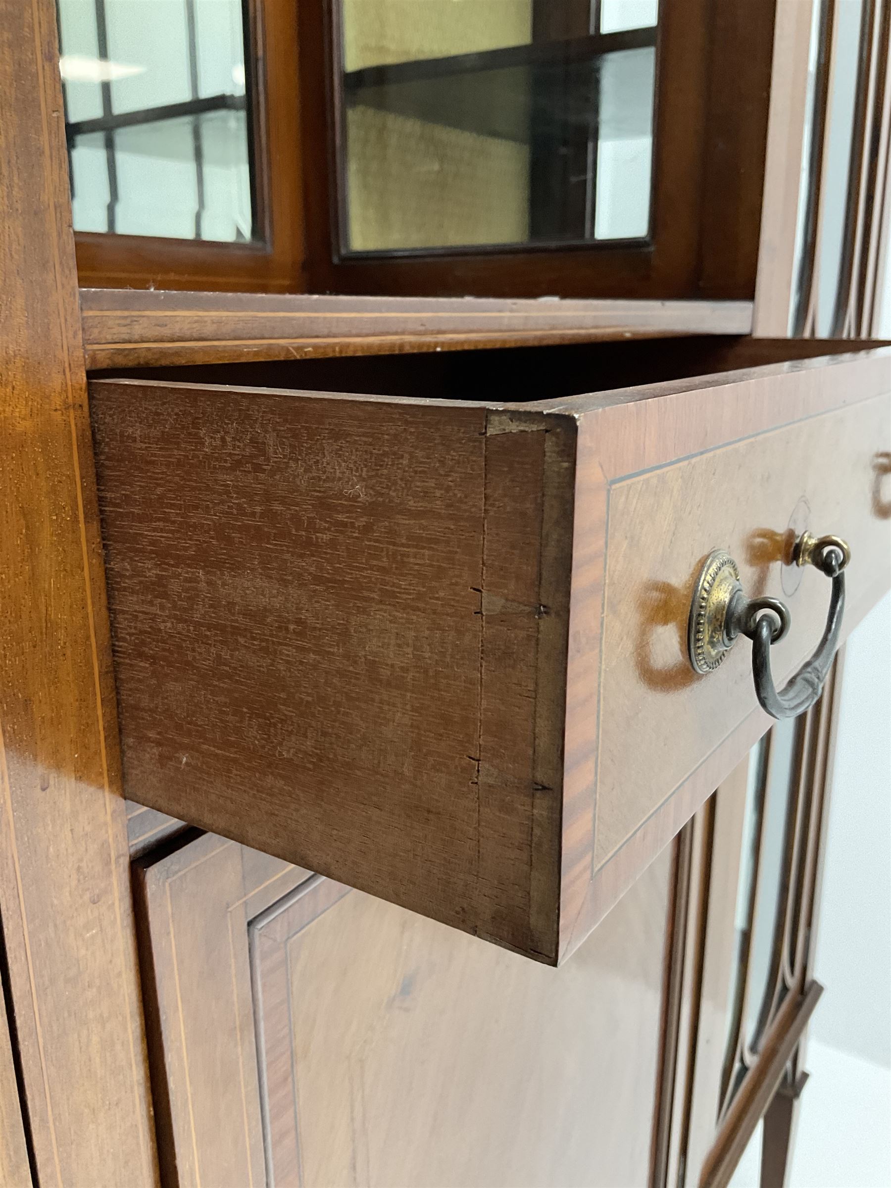 Edwardian inlaid mahogany display cabinet with ‘Shepard, Bennington & Co. Doncaster’ makers plaque, central bevel edge mirror flanked by two glazed doors enclosing two lined shelves, single drawer above cupboard on square tapering supports with spade feet