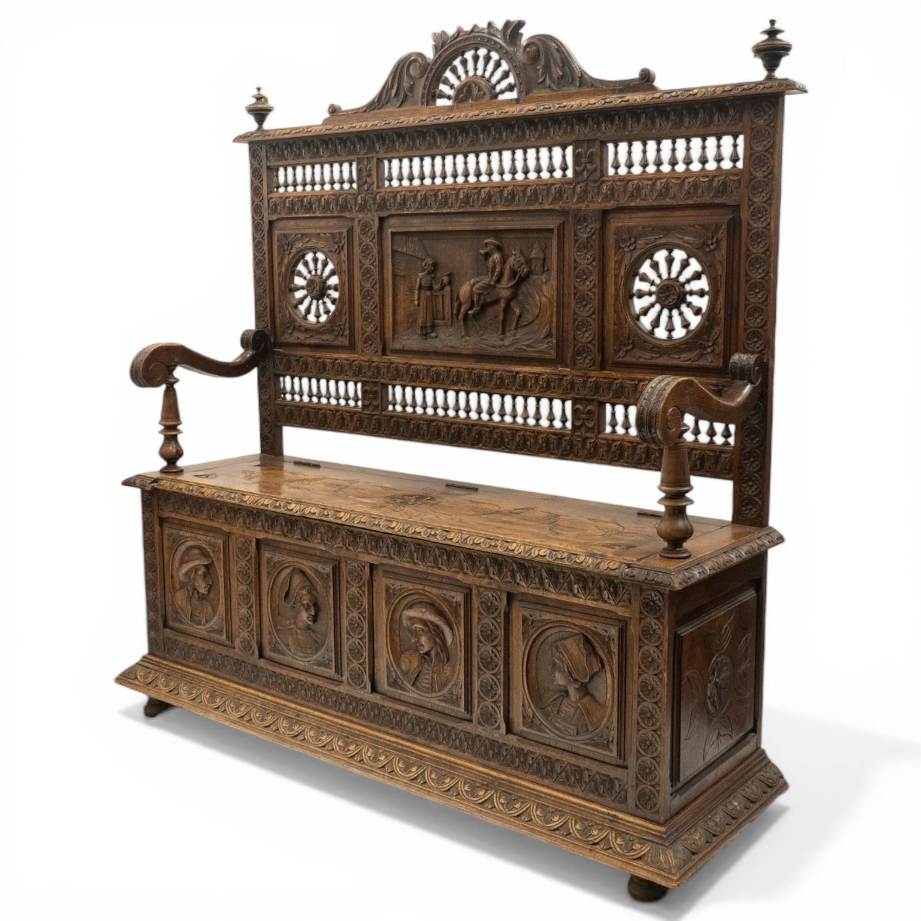 19th century European heavily carved oak hall settle, the impressive high-back with a pierced and carved acanthus pediment, over foliate and rosette carved back rails, flanking a central panel depicting a gentleman on horseback drinking, the hinged box seat over a quadruple panelled front with relief carved busts, lower moulded and carved edge on compressed bun feet