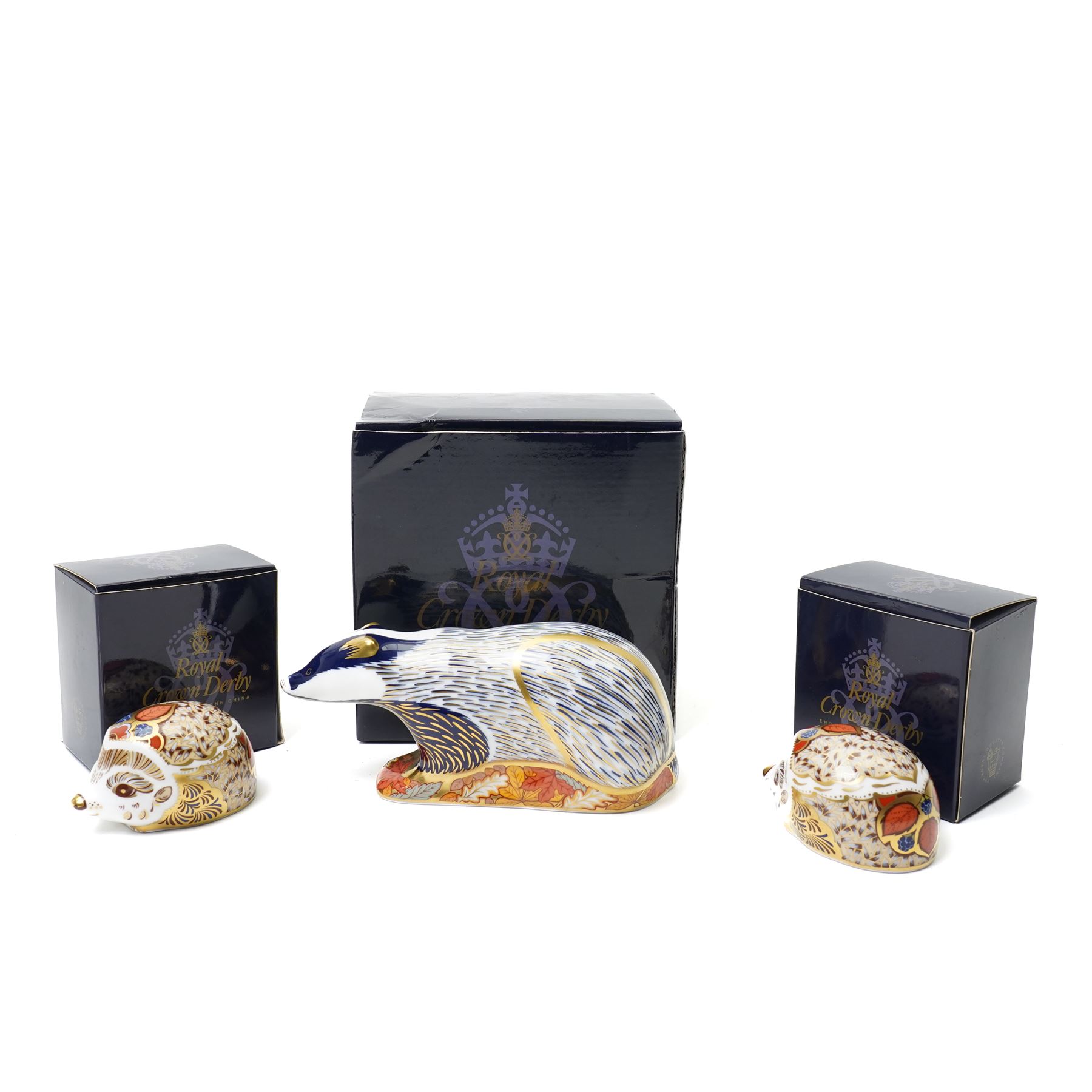 Three Royal Crown Derby paperweights, comprising two of Bramble the Hedgehog, with gold stopper, with boxes, and one of a Woodland Badger, with gold stopper, boxed (3)