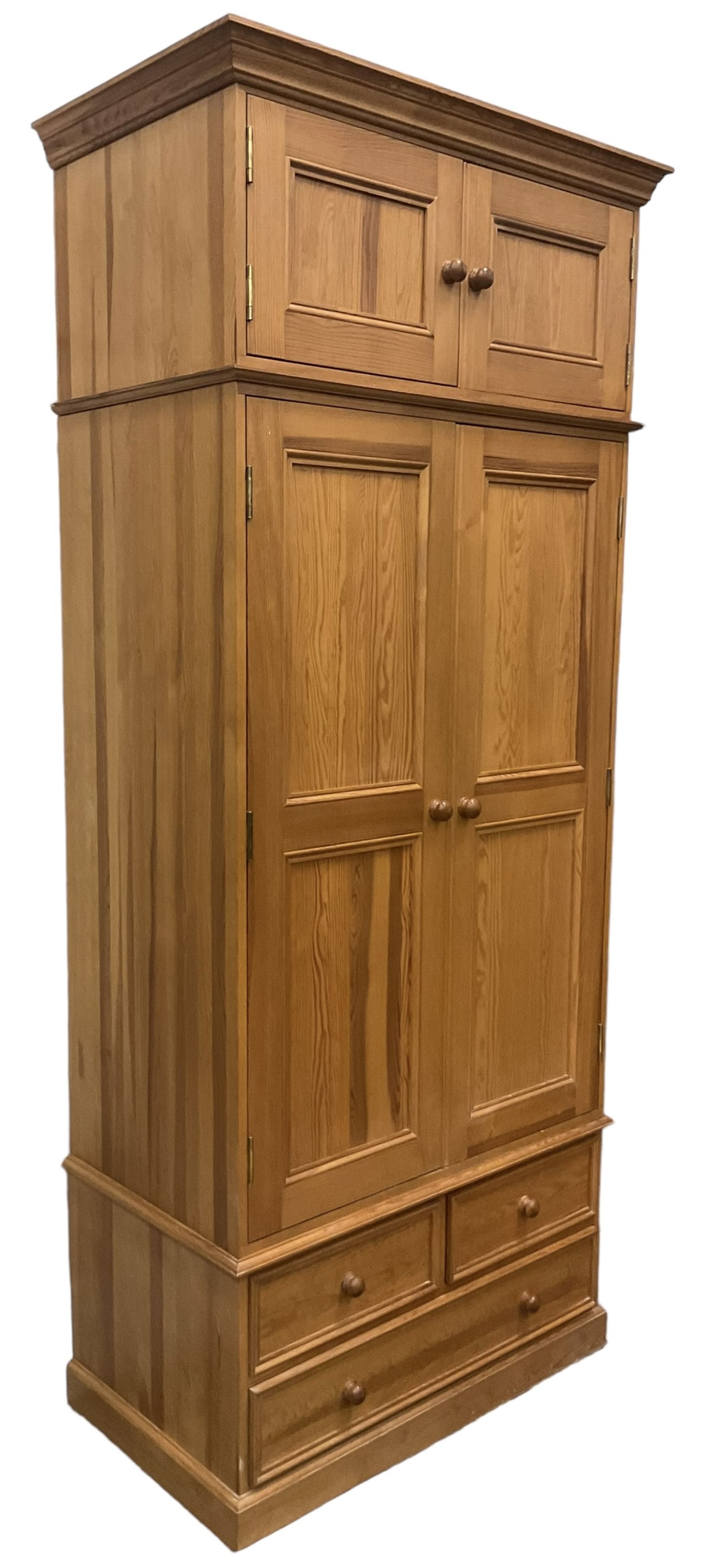 Solid pine double wardrobe, fitted with top box, enclosed by panelled doors, two short and one long drawer, on plinth base 