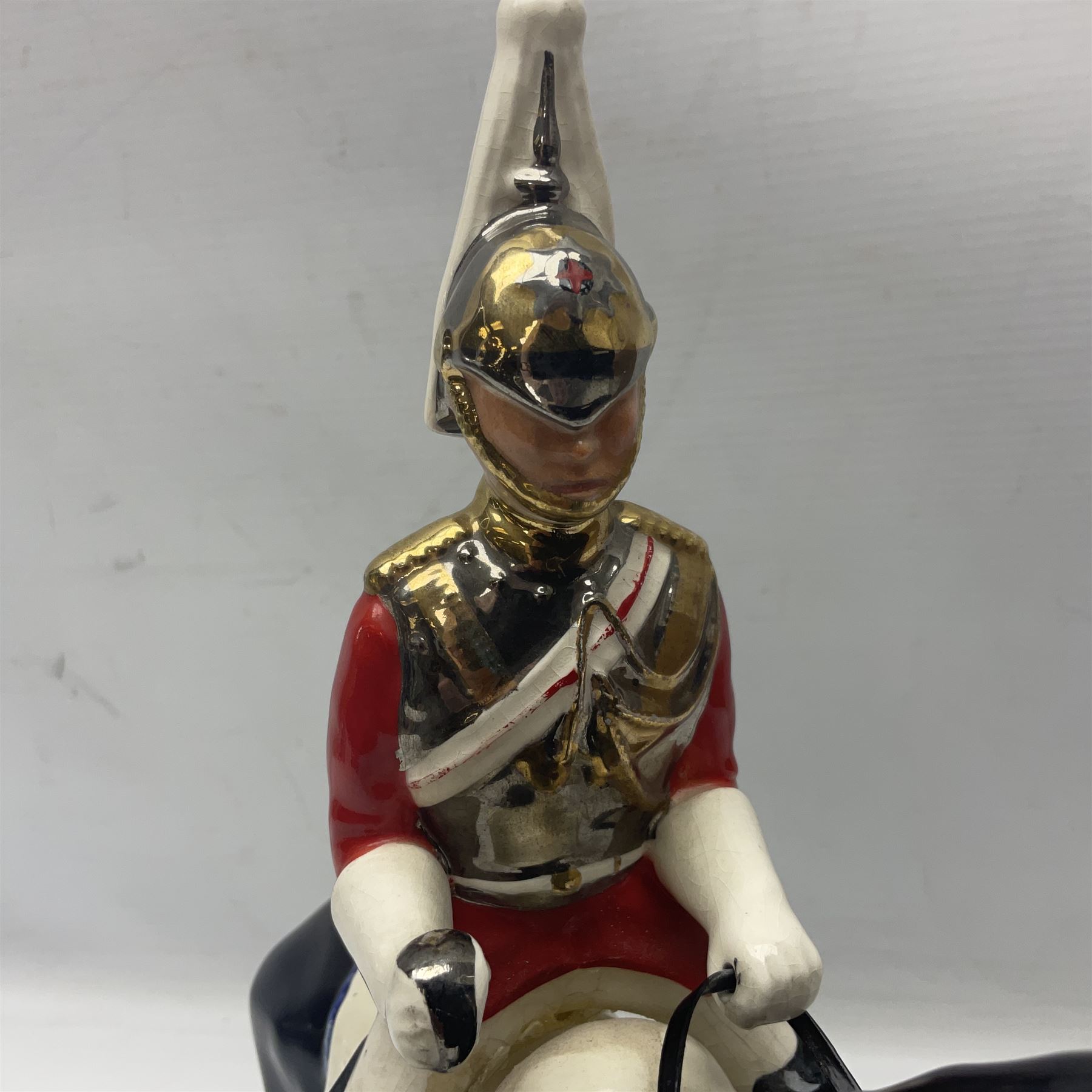 Mounted Lifeguard upon a black horse, in the style of Beswick, upon a wooden plinth, H31cm