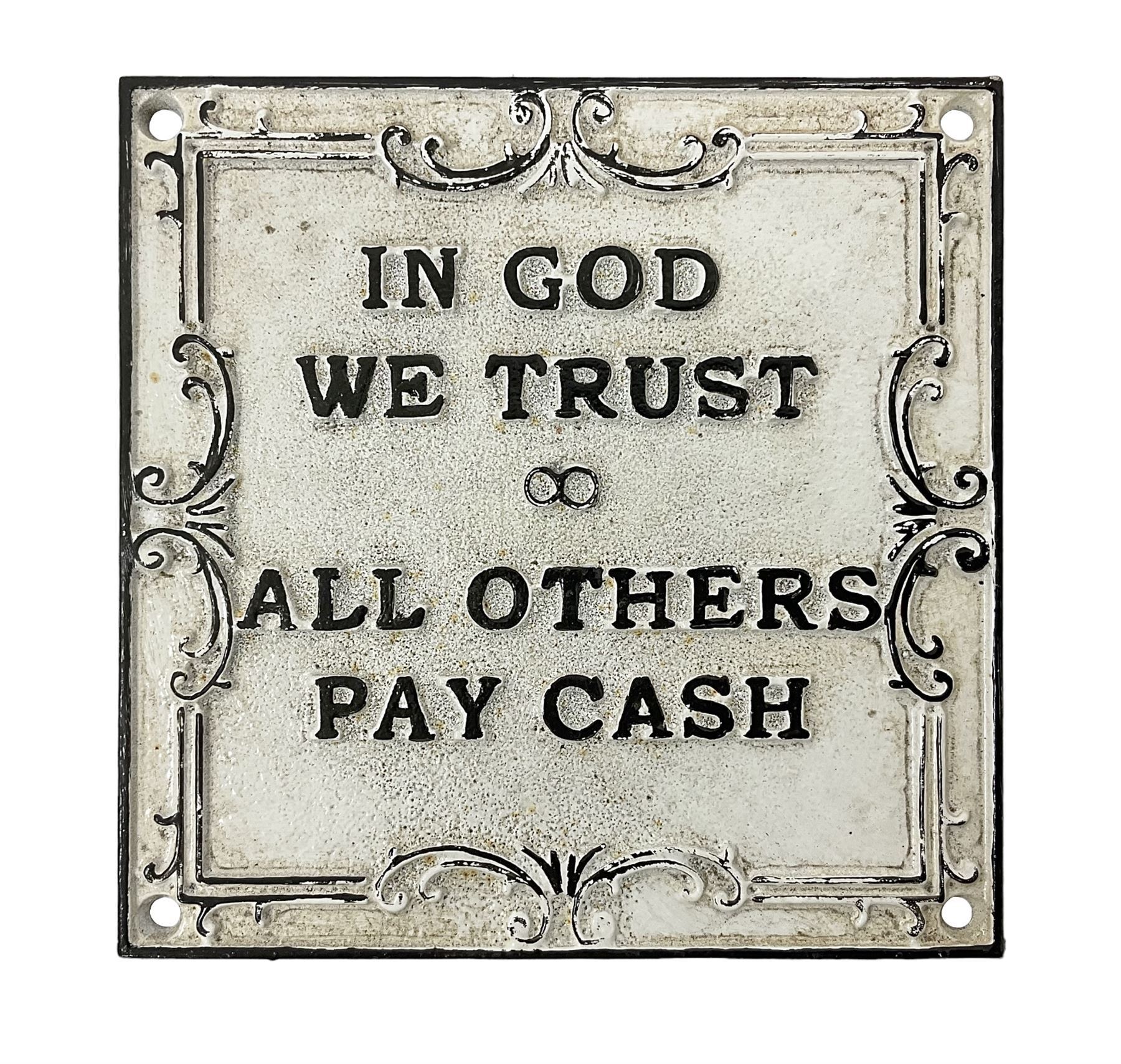 Cast iron 'In God we Trust' sign with black writing on a white ground, H15cm