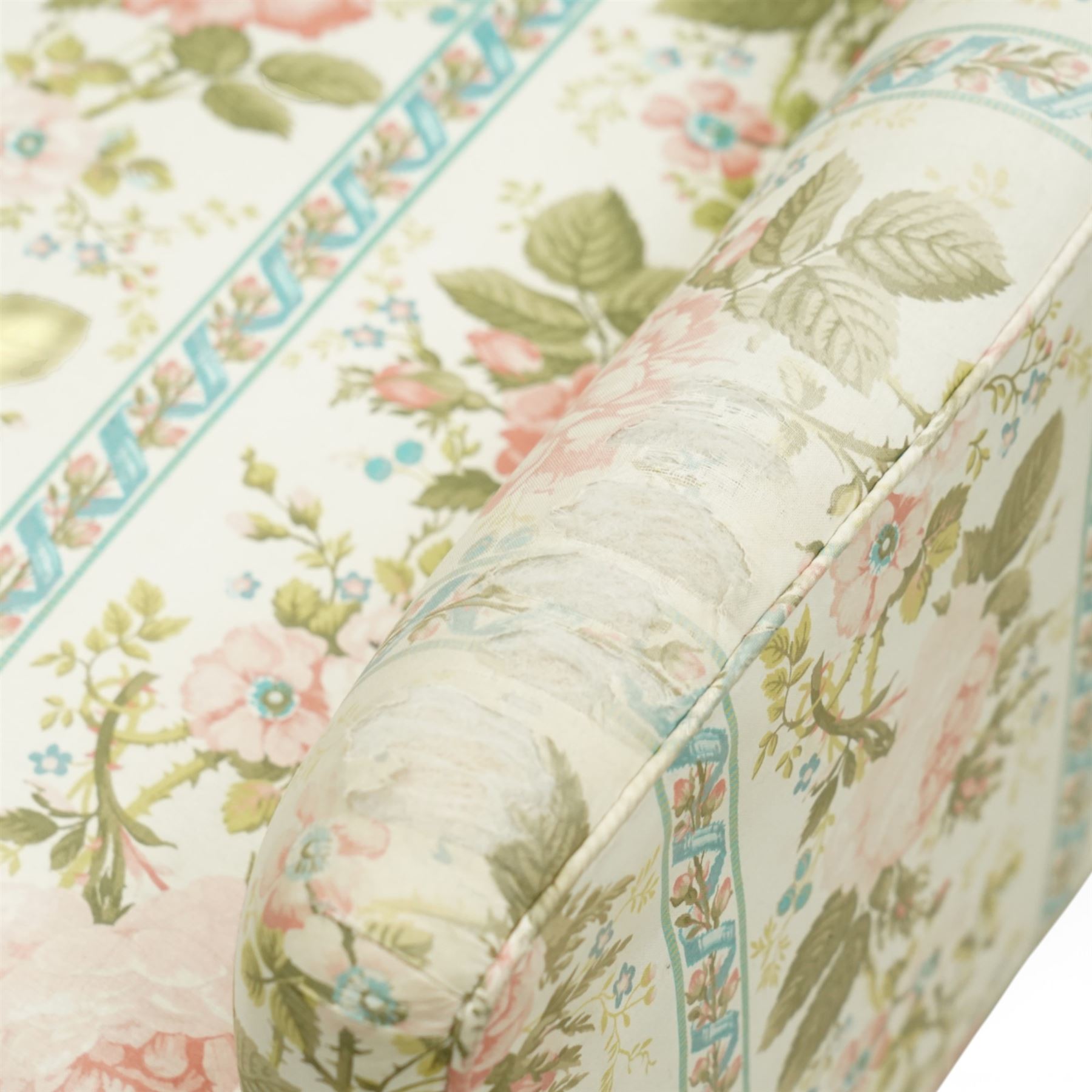 Pair of Edwardian upholstered armchairs, each with shaped padded back flanked by scroll arms, loose seat cushions, upholstered throughout in rose patterned fabric with vertical floral bands, raised on square tapering wooden legs