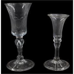 Two early/mid 18th century drinking glasses, the largest example with waisted bucket shaped bowl upon an inverted baluster stem with internal elongated tear and basal knop, and folded foot, H15cm, the smaller with bell shaped bowl upon a stem with two shoulder knops and basal knop, and folded foot, H12.5cm 