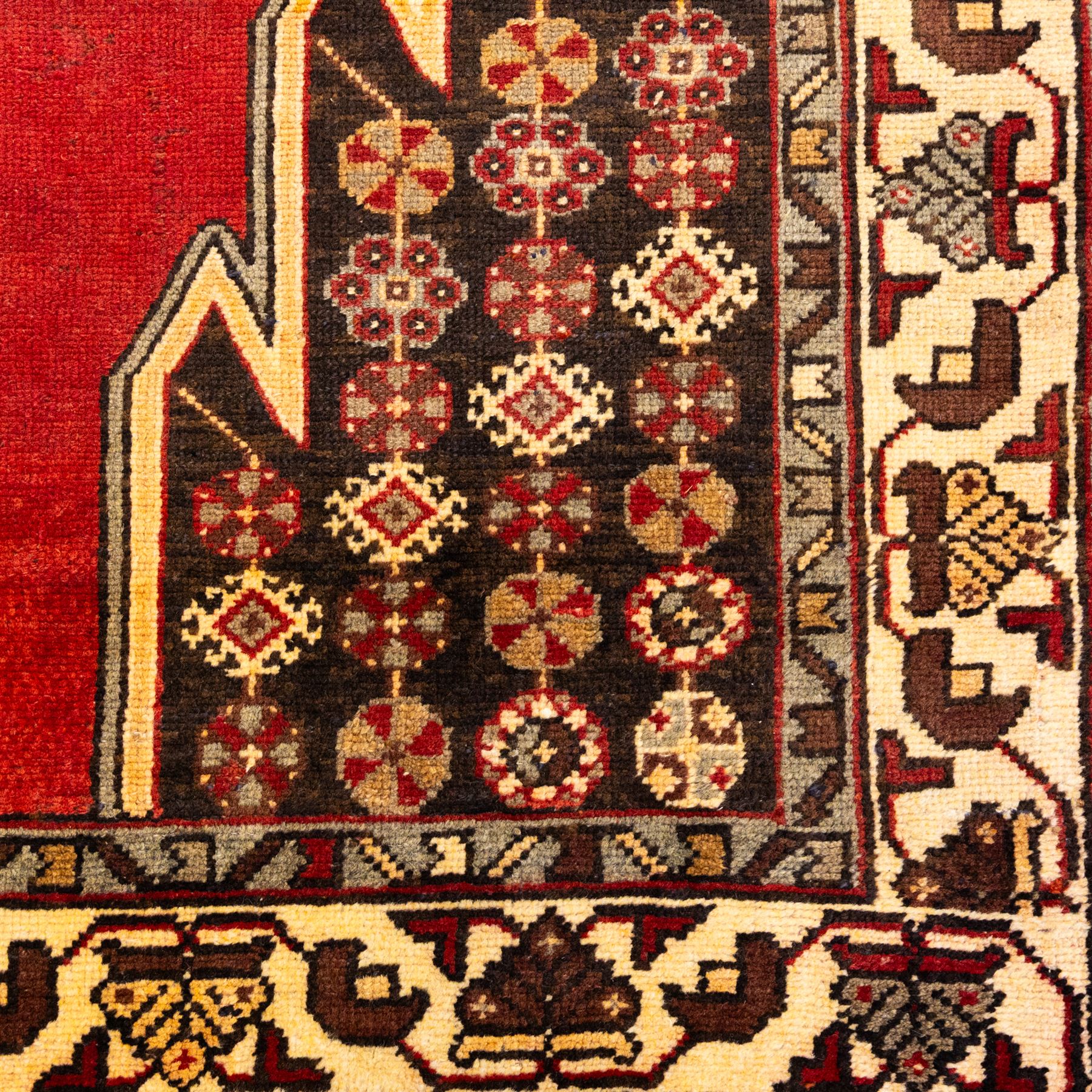 West Persian Mazlaghan hand-knotted rug, madder red field with central stepped lozenge medallion with pendant motifs flanked by angular serrated spandrels filled with small geometric devices, enclosed within multiple borders featuring stylized floral and geometric motifs, with cotton fringe ends 