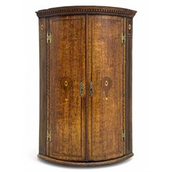 George III oak bowfront corner cupboard, the dentil-moulded cornice above twin doors inlai...