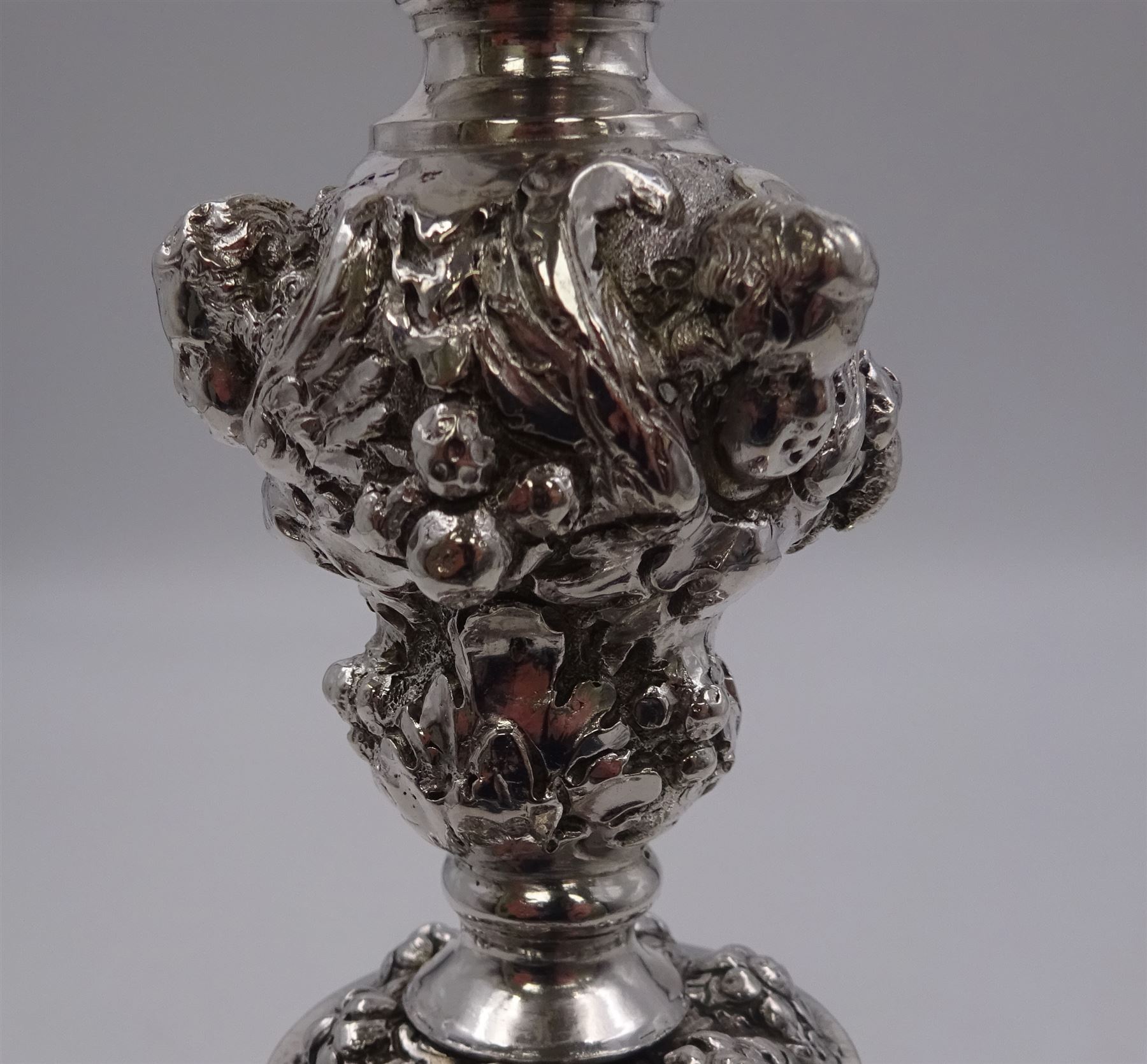 German silver chalice, the bowl, stem and foot each with 19th century repousse and chased decoration depicting putti masks, C scrolls and flowers, set with two hand painted porcelain roundels, possibly Berlin, and six later applied enamel roundels, each depicting religious scenes, the gilded bowl upon knopped stem and spreading octofoil foot, the base with marks for Munich, c.1695 and maker's mark FK