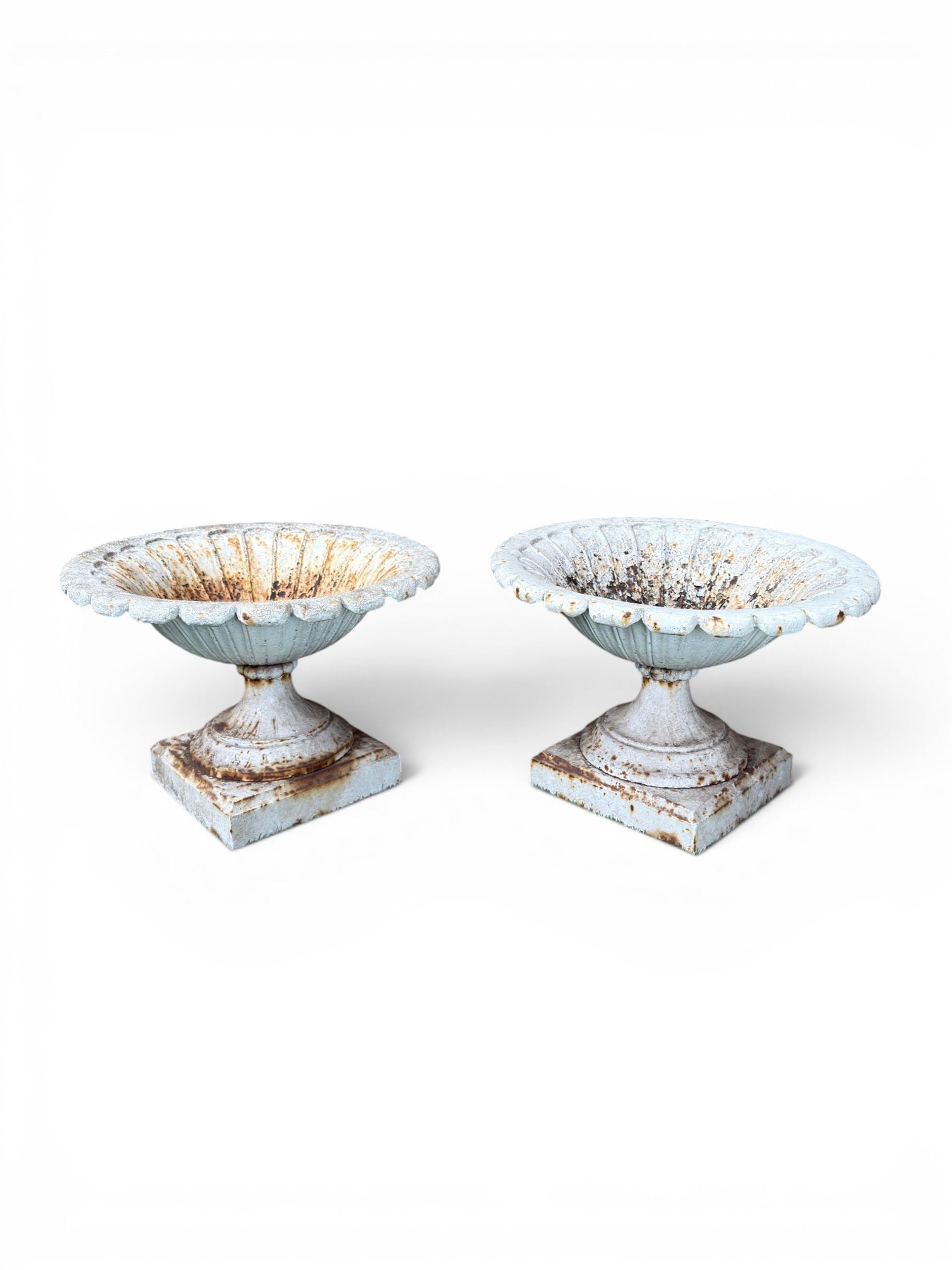 Coalbrookdale - pair of 19th century cast iron petal rim urns, squat form on square plinth, finished in distressed white paint, design registration number 133334, first registered 19 september 1860, number 19 in the Coalbrookdale Castings Catalogue (see illustration)