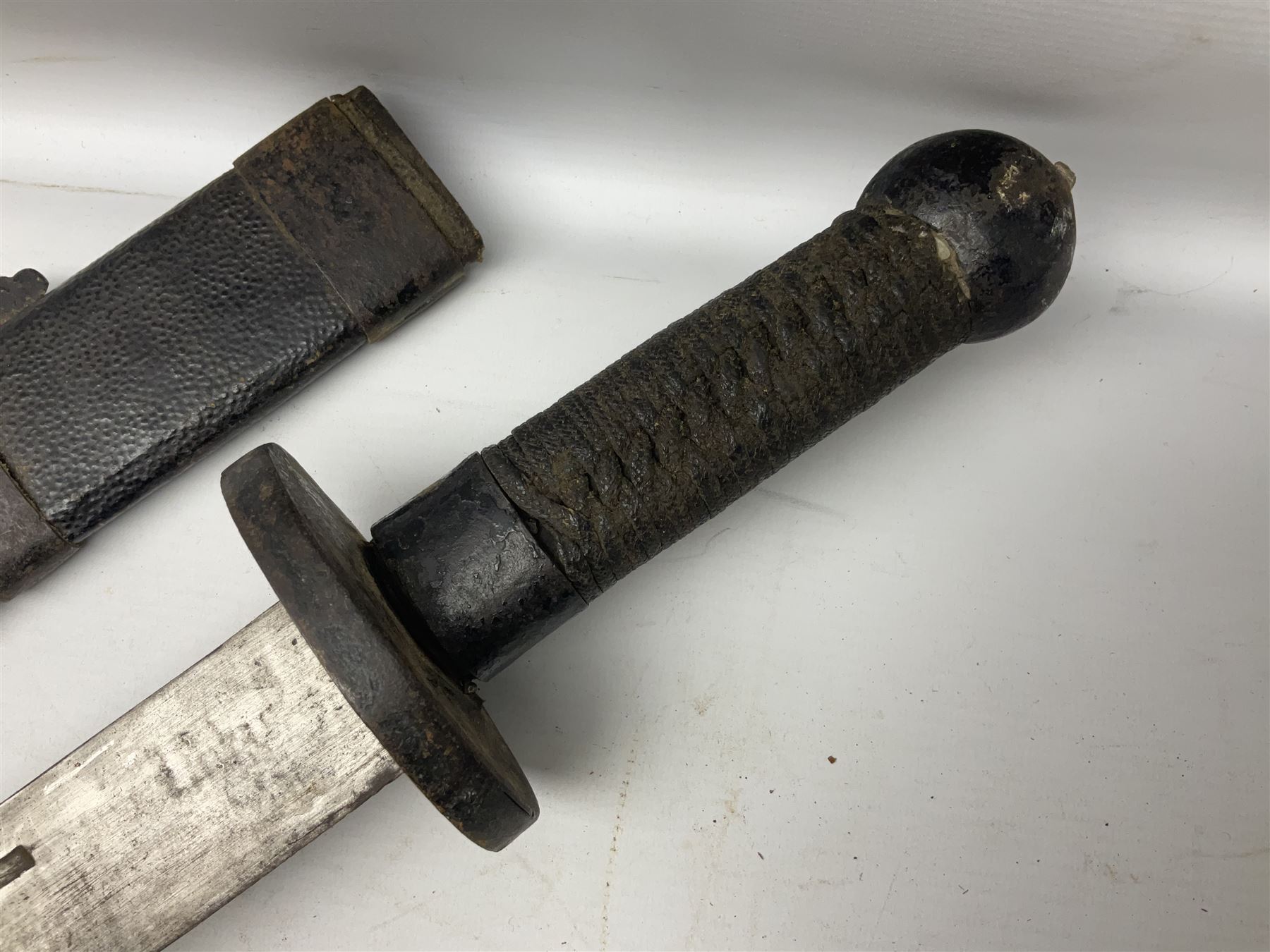 Chinese Boxer Rebellion Period Sword, 69.5cm heavy curved single edge blade with single narrow fuller, plain iron dished circular guard, iron pommel and ferrule with plaited cord bound grip; in skin covered wooden scabbard with iron chape and long suspension mount L95cm overall