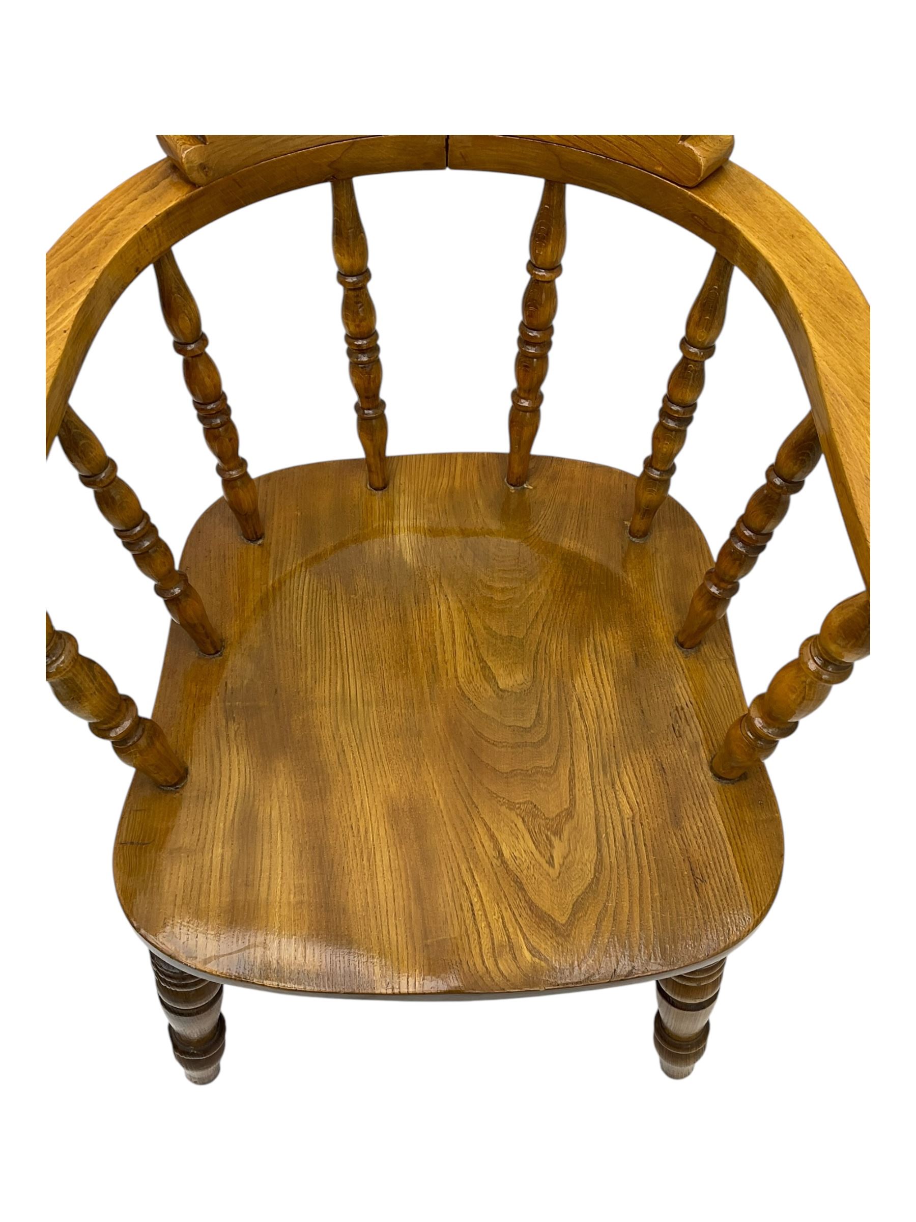 Late 19th century elm smoker’s bow armchair, curved top rails over turned spindle backs, shaped seats, raised on turned legs united by turned stretchers; together with a similar smoker’s bow armchair (2)