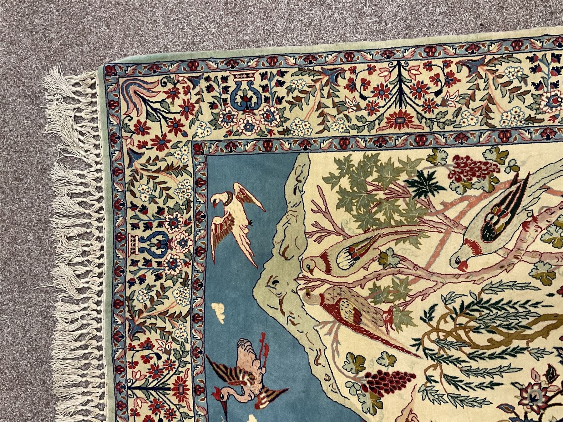 Fine Persian tree of life rug wall hanging, ivory ground field depicting landscape filled with animals, birds and flowers, the guarded border with stylised flower heads and foliage decoration, with brass hanging rail