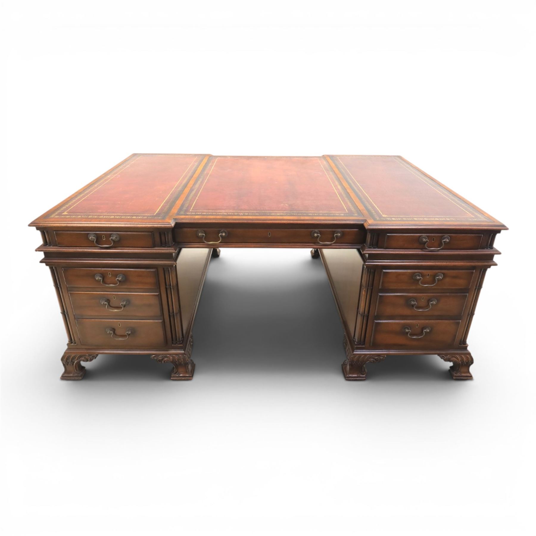 George III style large mahogany reverse breakfront partners desk, red tooled leather writing surfaces crossbanded and moulded edges, flanked by ring-turned cluster columns three frieze drawers with brass swan neck handles, raised on large pedestals with faux drawer fronted cupboard and three graduated drawers, supported on carved ogee feet decorated with C-scrolled and acanthus leaves