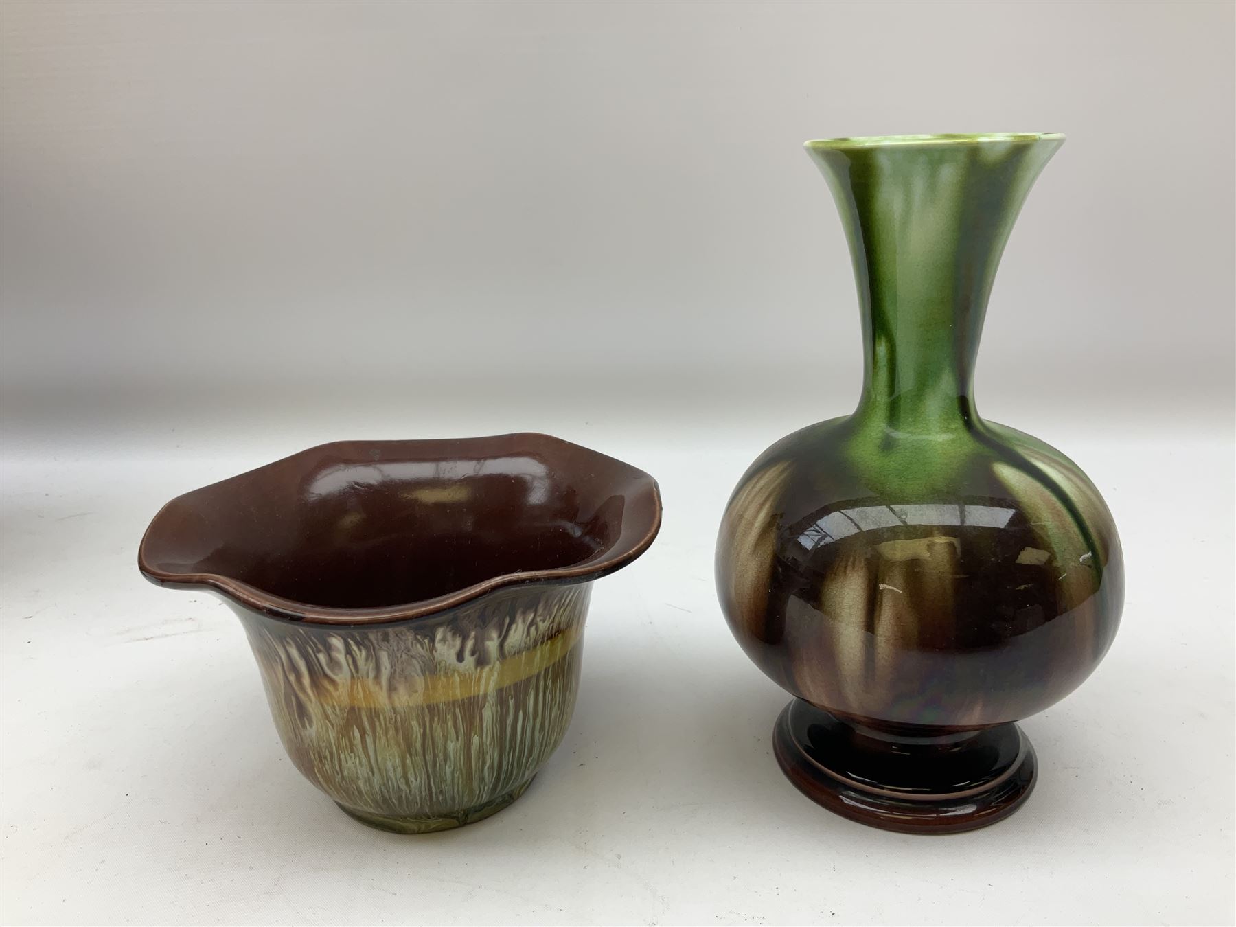 Linthorpe pottery vase with crimped rim and ovoid body, Linthorpe jug with high loop handle and crimped spout, a pair of candlesticks with a green, brown glaze and other similar pottery 