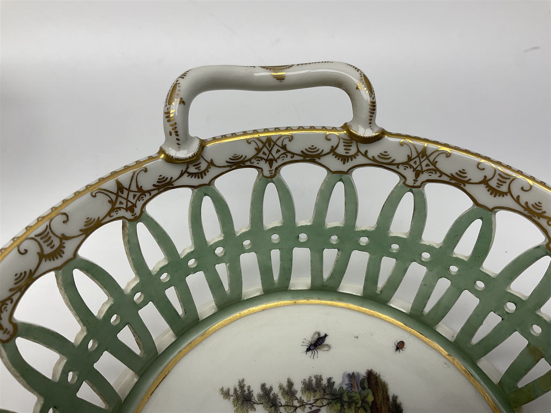 Pair of 19th century German openwork chestnut baskets, with twin handles and scrolling gilt border and star rim, painted to the centre with birds and insects, D22cm 