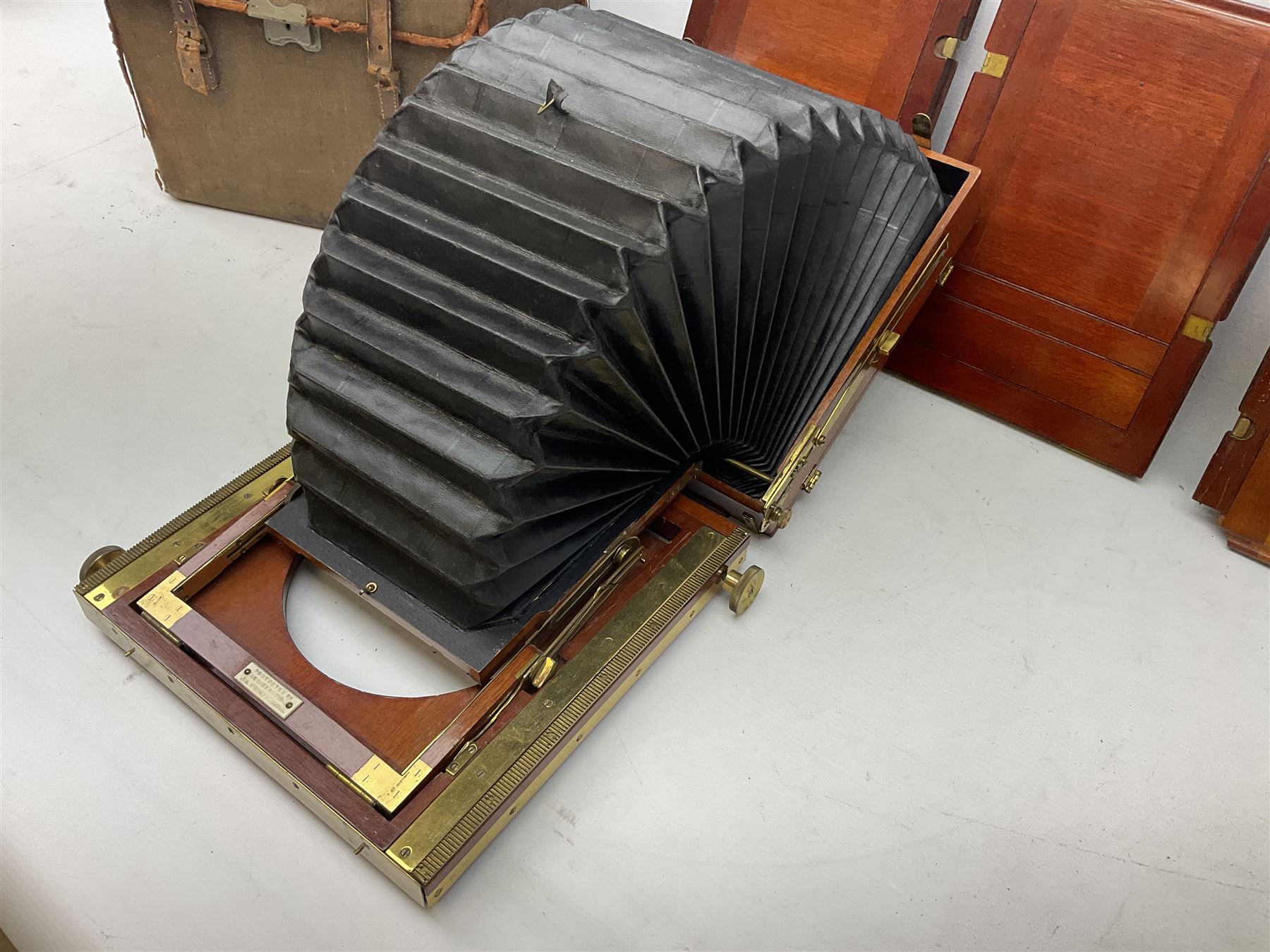 Thornton Pickard folding plate camera in mahogany and lacquered brass, no.529946 and no.529947, field model with canvas wrapped box, three mahogany photographic plates, 'Busch's Portrait Aplanat No4 Foc.14inc' lens and a wooden tripod