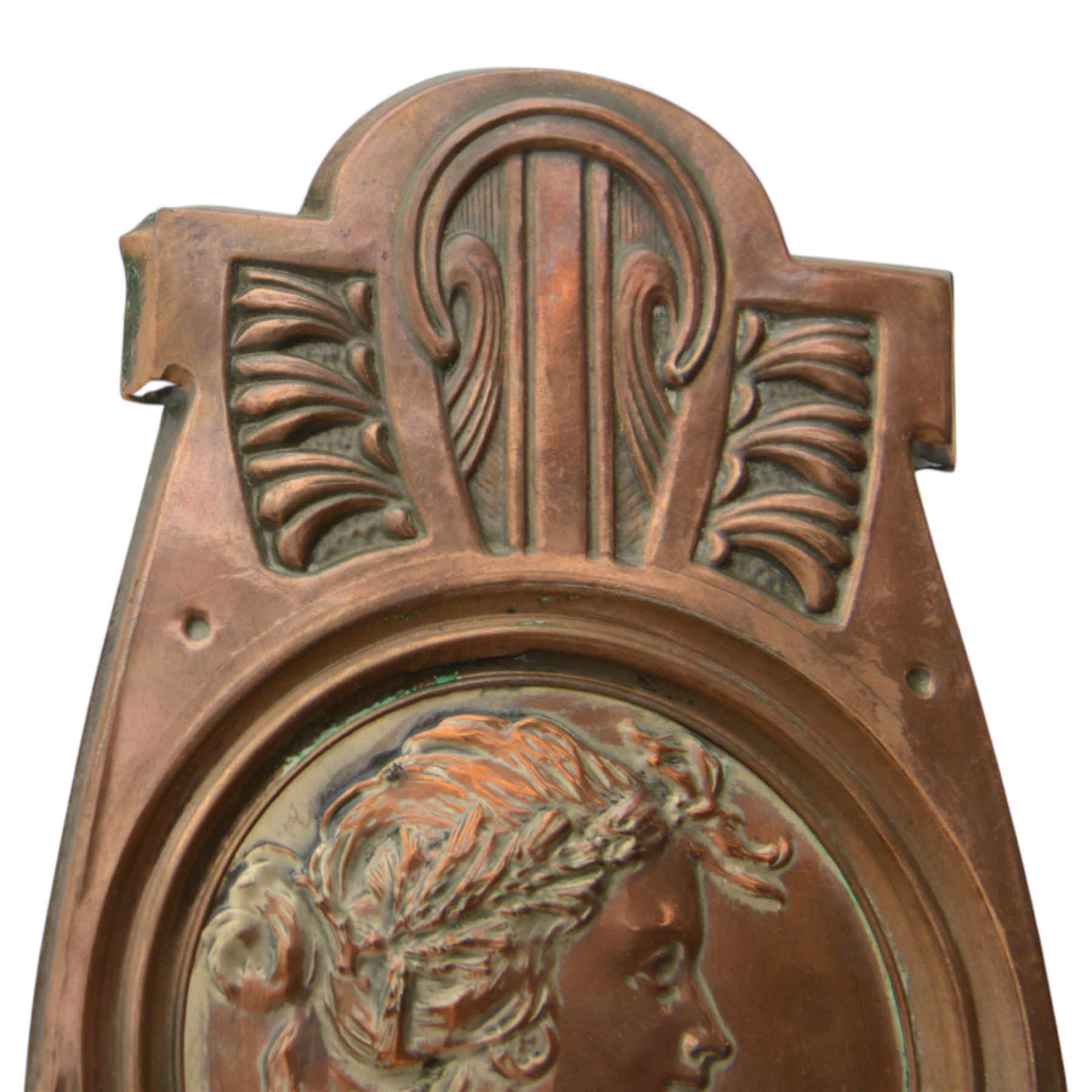 Pair of late 19th/early 20th century Art Nouveau copper twin branch wall sconces, each with shaped back plate chased with a central panel of a maiden in profile above and surmounted by foliate motifs, supporting two foliate open cast branches with bud sockets above conforming drip pans, H31cm W16cm D8.5cm
