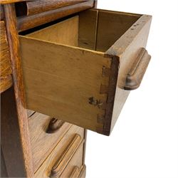 Early 20th century oak roll-top desk, the tambour enclosing pigeon holes and small drawers, the base fitted with slide, a single long drawer and three smaller drawers