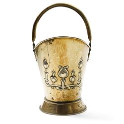 Art Nouveau brass log bucket of oval design with swing handle and a raised pattern of stylised flowers H29cm