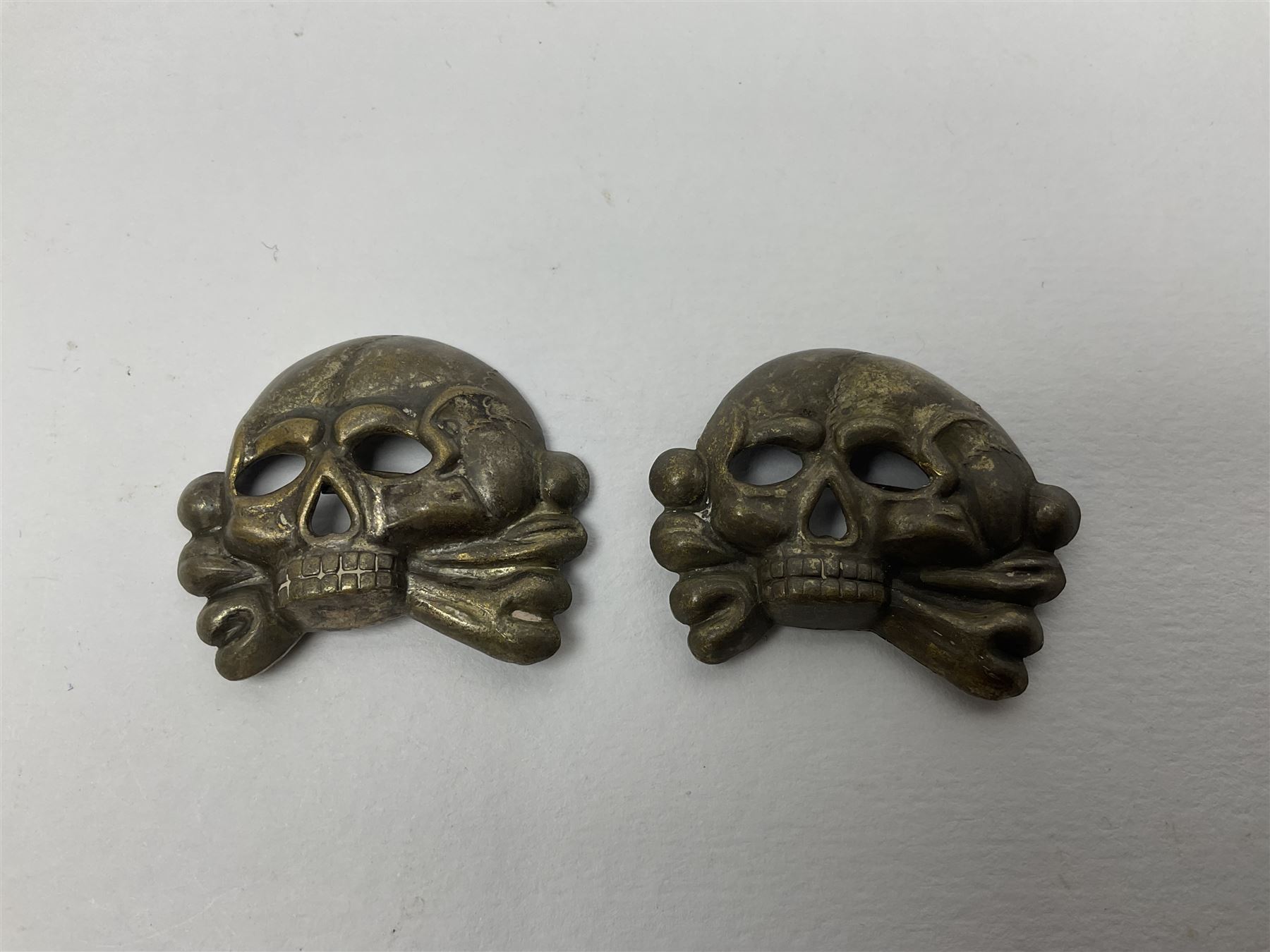Five German 'SS' visor cap metal badges comprising one eagle and four skull and cross-bones (5)