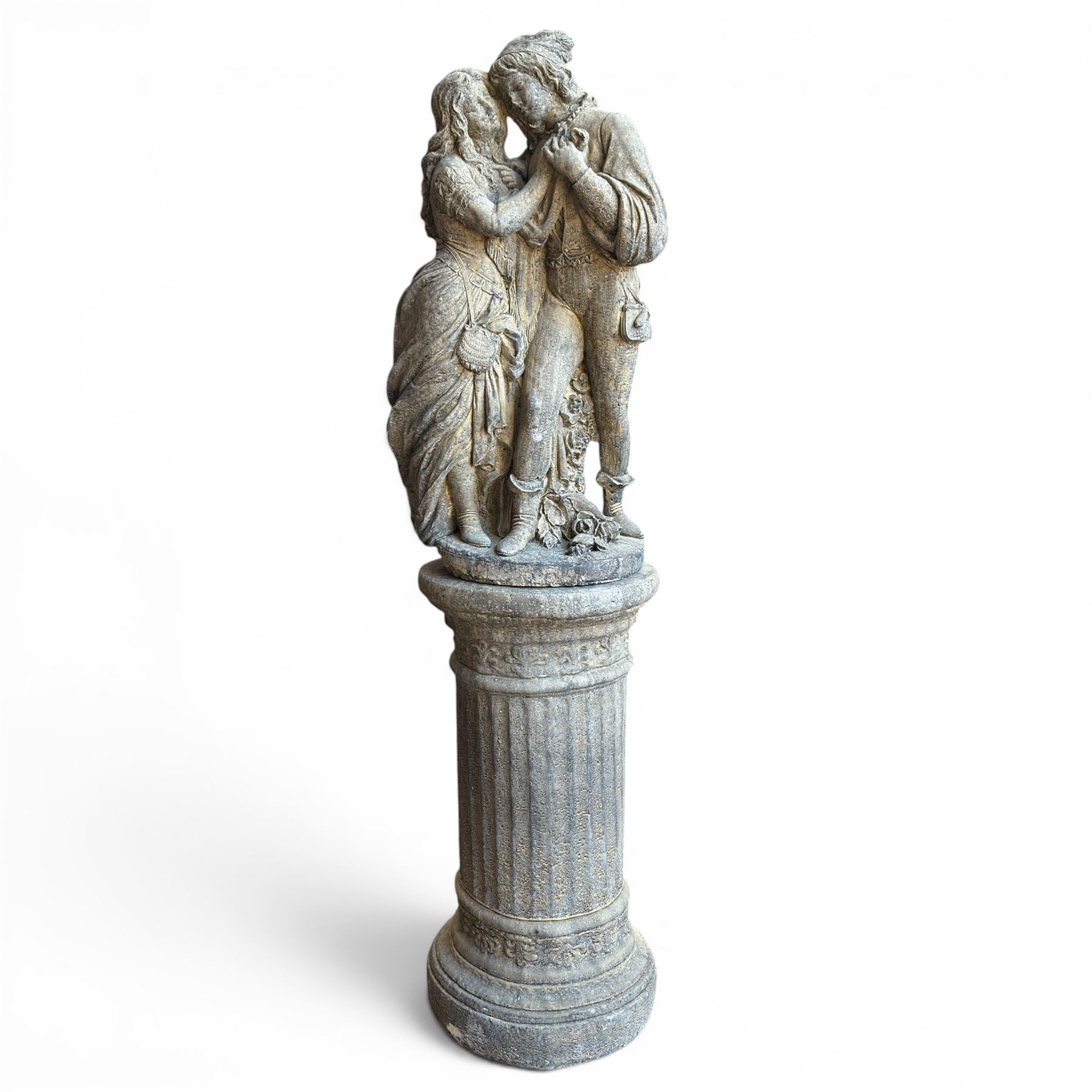 Composite garden statue group of Romeo and Juliet embracing, the couple adorned in Medieval dress standing on a naturalistic base with fallen flowers, raised on a Neoclassical fluted pedestal with Anthemion leaf motifs
