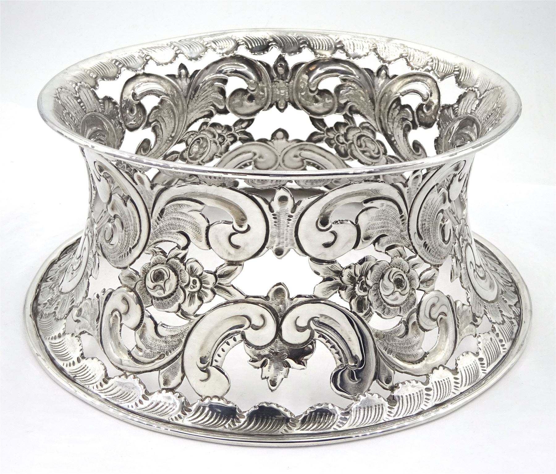 Edwardian silver dish ring in the Irish manner, of circular waisted form, embossed and pierced throughout with flower heads and foliate and C scrolls, hallmarked I S Greenberg & Co, Birmingham 1904, with accompanying blue glass liner, upper rim D17.5cm, approximate weight 6.84 ozt (213 grams)