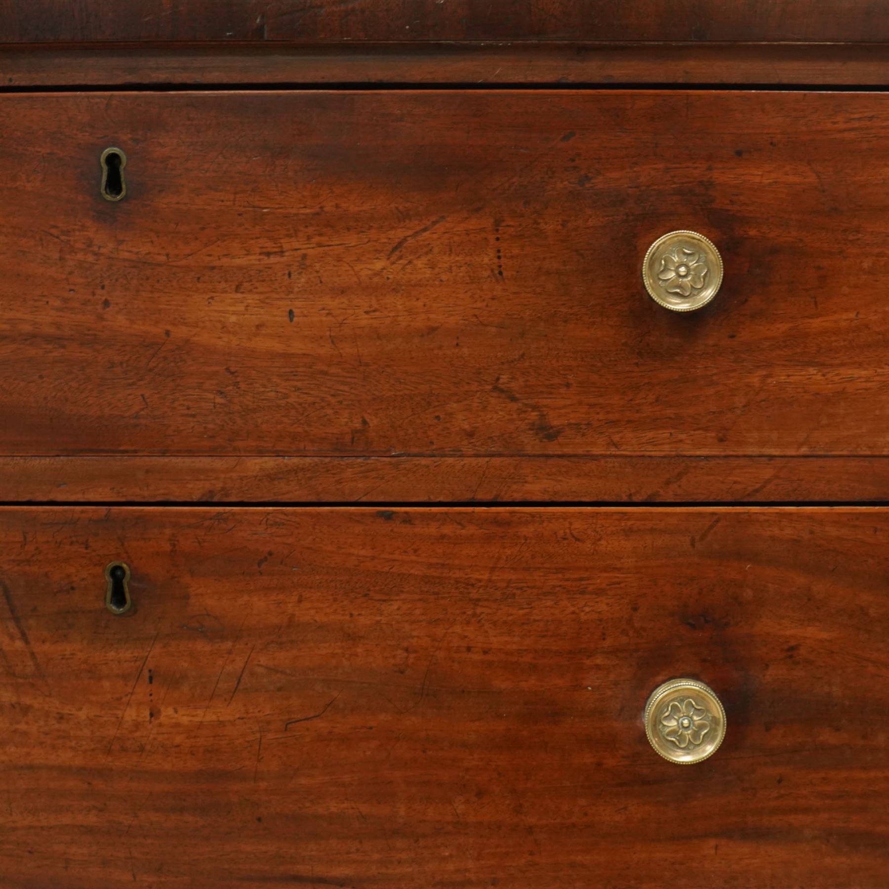 Late George III mahogany bow-fronted chest, the moulded top over three long graduating drawers fitted with turned brass knobs and brass-lined escutcheons, the shaped apron and splayed bracket supports
