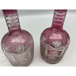 Pair of late 19th/early 20th century cranberry flash cut glass decanters, the bodies with Prussian shoulder with cross hatching, hobstar and hobnail decoration, four band necks, star cut bases and faceted stoppers, H30cm