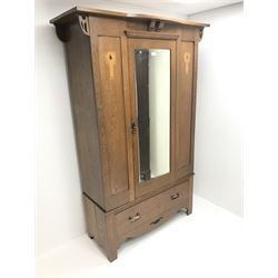 Arts and Crafts period oak wardrobe, projecting shaped cornice, single bevel edged mirrored door above drawer