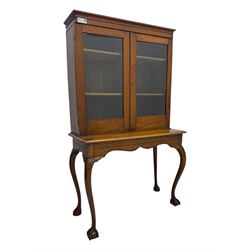Late 19th century oak display cabinet, rectangular form with a pair of glazed doors enclosing shelves, raised on cabriole supports with carved detailing ending in claw feet