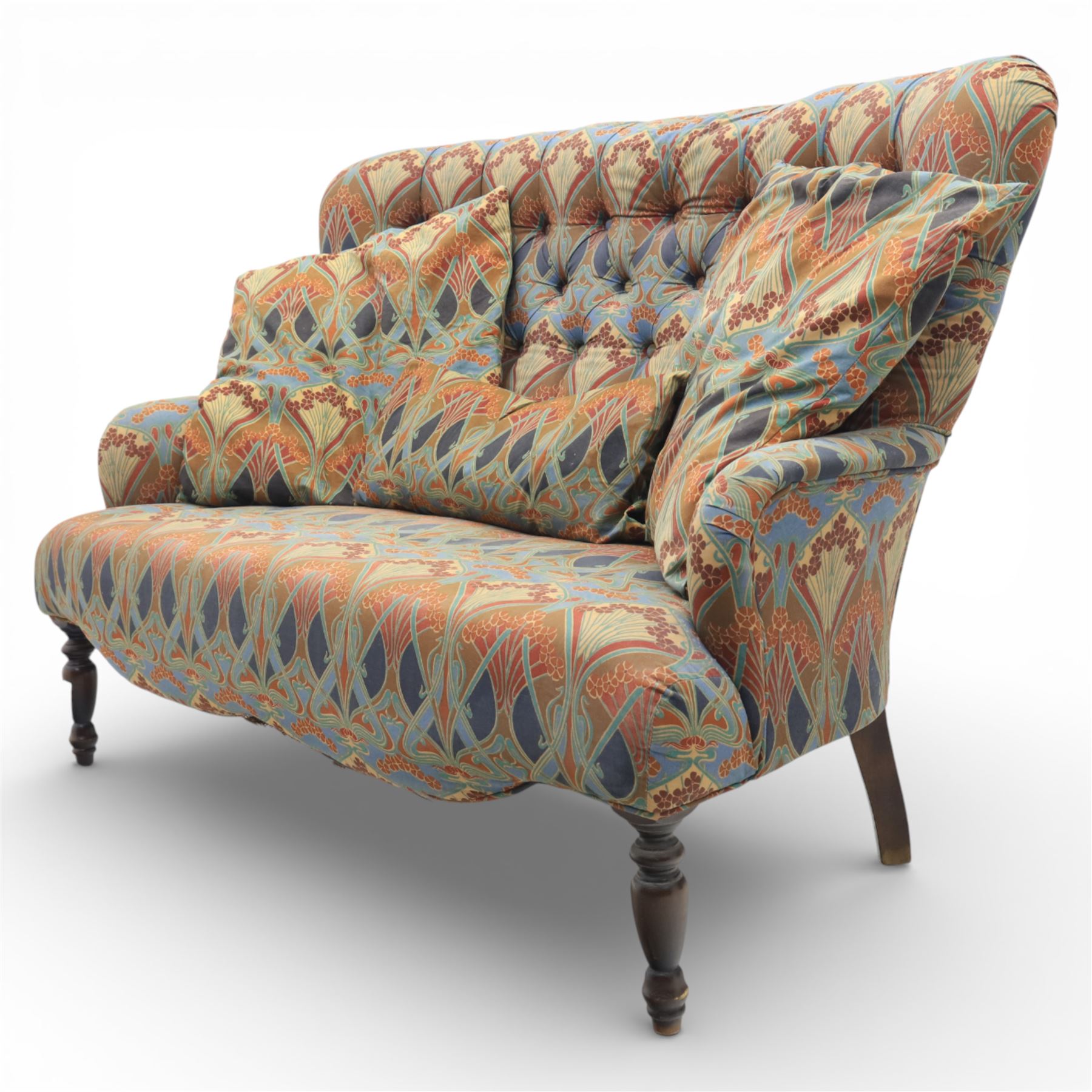 Late 20th century Liberty upholstered two seater sofa, the shaped back and arms with deep buttoned upholstery, covered in Art Nouveau fabric with stylised floral and foliate motifs, loose scatter cushions en suite, raised upon turned tapering front supports and swept rear legs