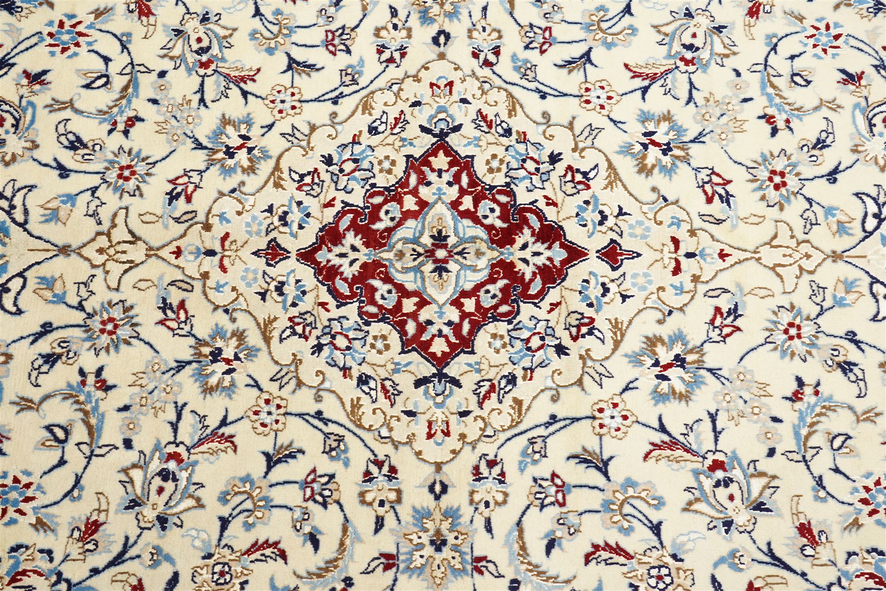 Central Persian Nain hand-knotted rug, ivory field with central medallion in tones of indigo and blue, issuing vinery, palmettes and floral sprays with conforming spandrels, dark blue main border of floral vinery and stylized palmettes, framed by multiple guard borders, with cotton fringe ends 