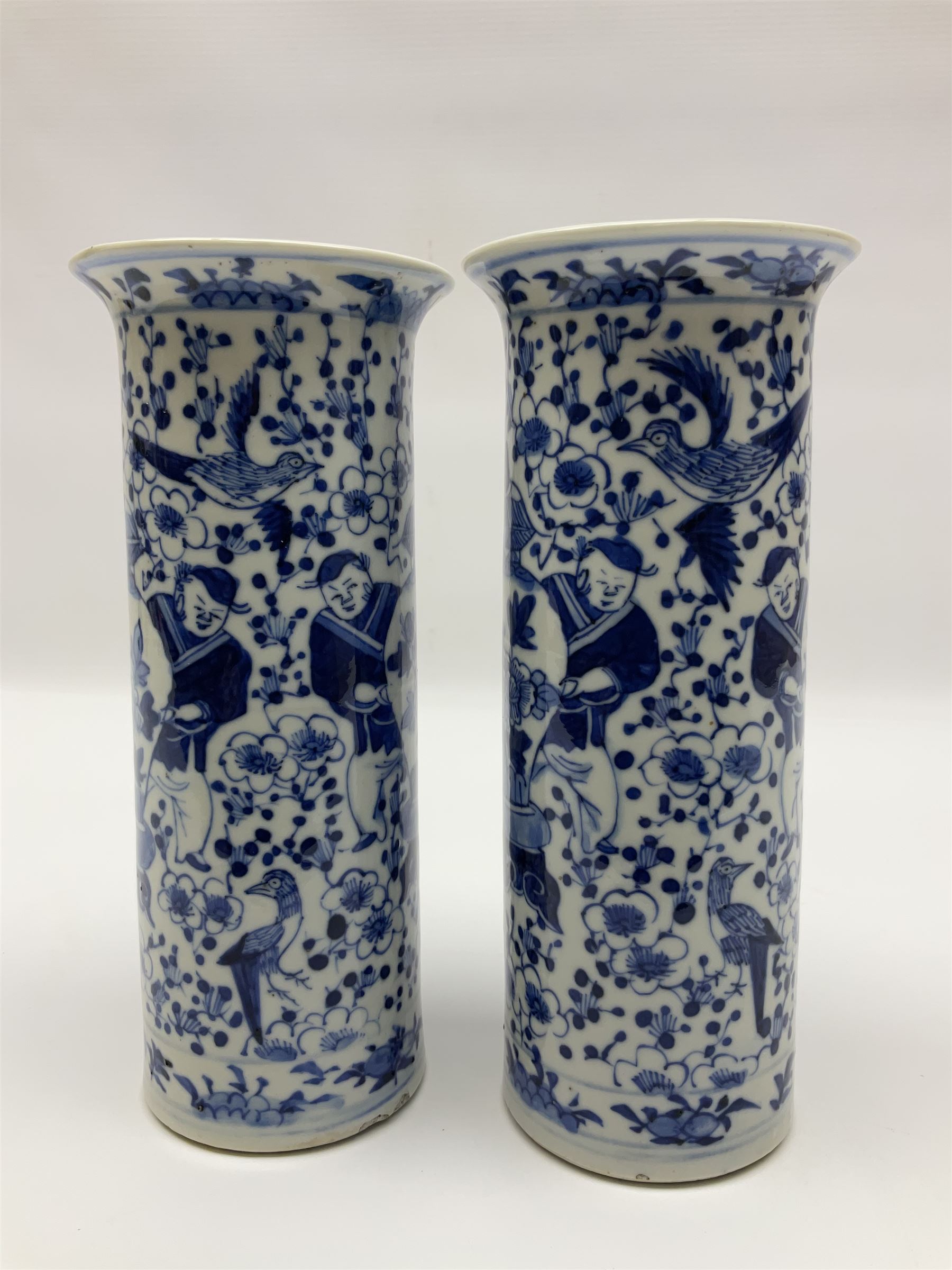 Pair of Chinese blue and white cylindrical vases, decorated with bird and flowers surrounding central figures holding a large vase, H20cm