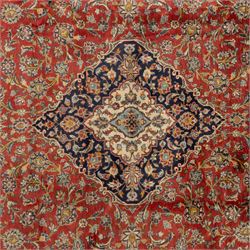 Persian Kashan carpet, the field in rich rust tone centred by an ivory and blue medallion with palmette extensions, surrounded by intricate foliate arabesques and stylised blooms, within triple floral borders incorporating palmettes and interlaced tendrils, woven in the region of Kashan