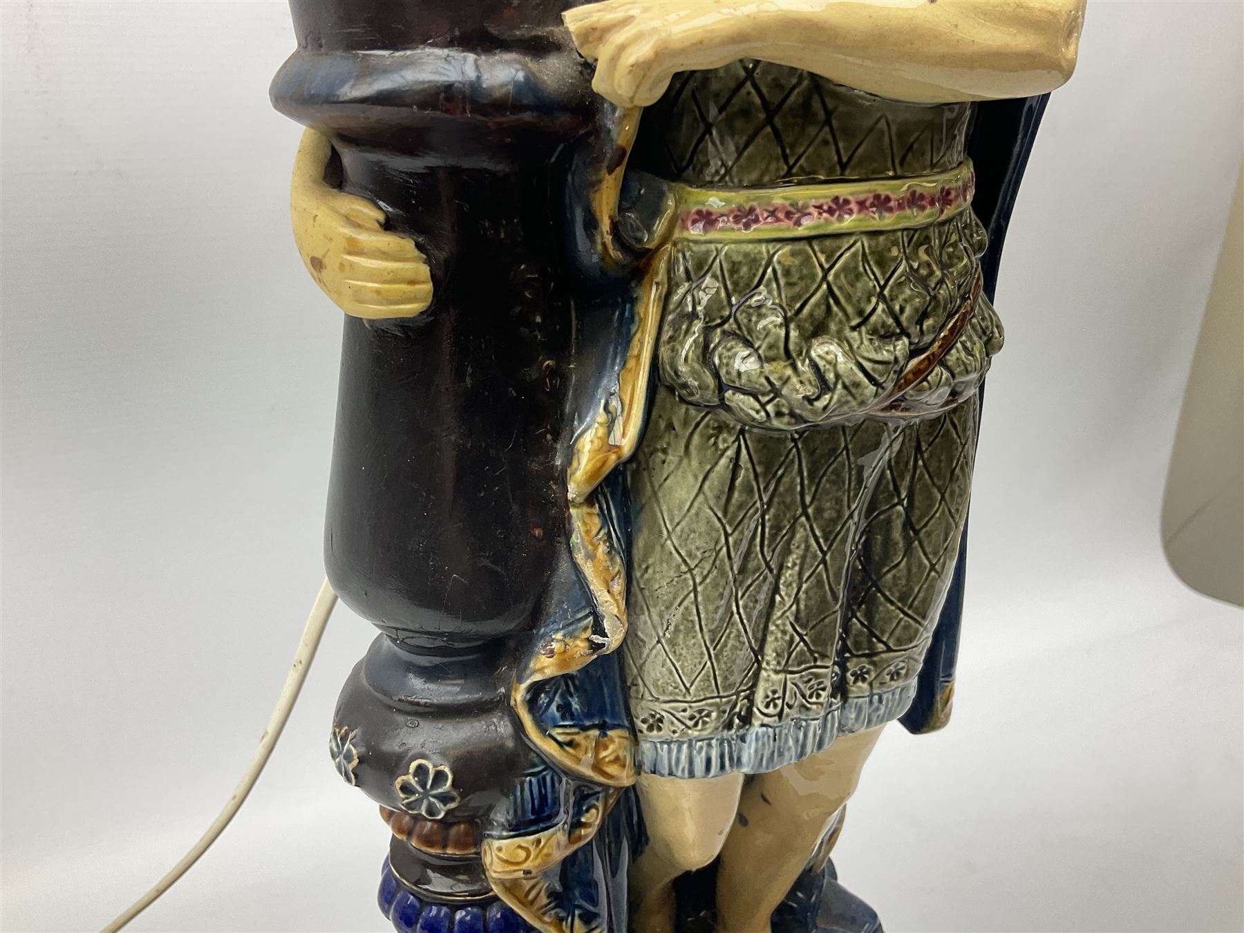 Composite table lamp modelled as a Roman Emperor donning blue robes, upon quatrefoil base modelled with rams heads and winged cherubs, H56cm excl fitting