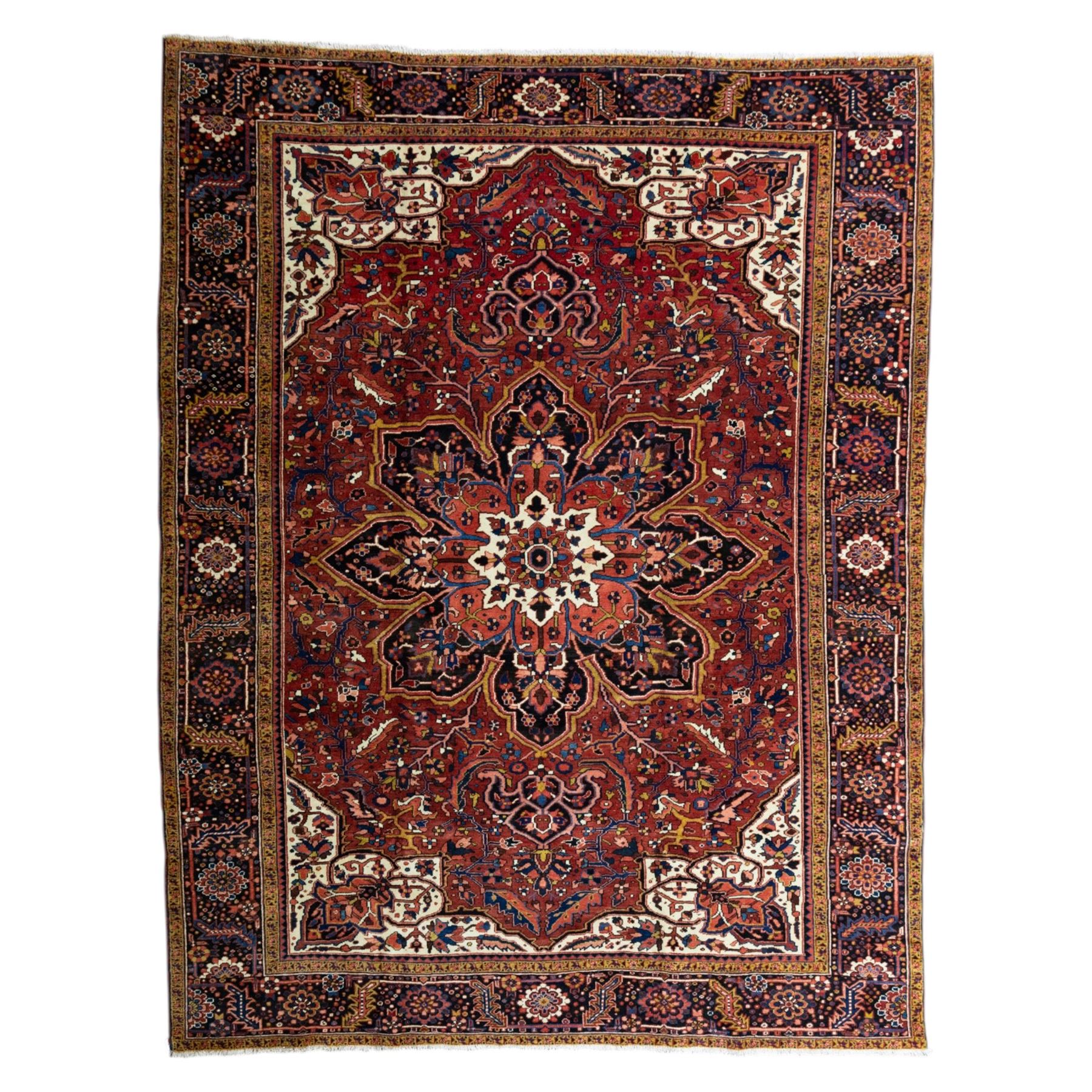 North West Persian Ahar hand-knotted carpet, madder red ground, with a large central shaped floral medallion with pendants, surrounded by angular scrolling foliate motifs incorporating rosettes, palmettes and stylised flowerheads, enclosed by ivory spandrels and a dark navy border with repeating floral motifs and meandering vines, flanked by narrow floral guard stripes, with cotton fringes