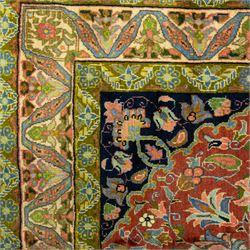 South Persian Sirjan hand-knotted carpet, terracotta ground, with a central shaped dark navy floral medallion with pendants, surrounded by scrolling foliate and floral motifs incorporating palmettes, rosettes and stylised vine work in blue, green and ivory tones, enclosed by dark navy spandrels and a wide green and ivory border with repeating palmettes and angular leaf motifs, flanked by patterned guard stripes, with cotton fringes