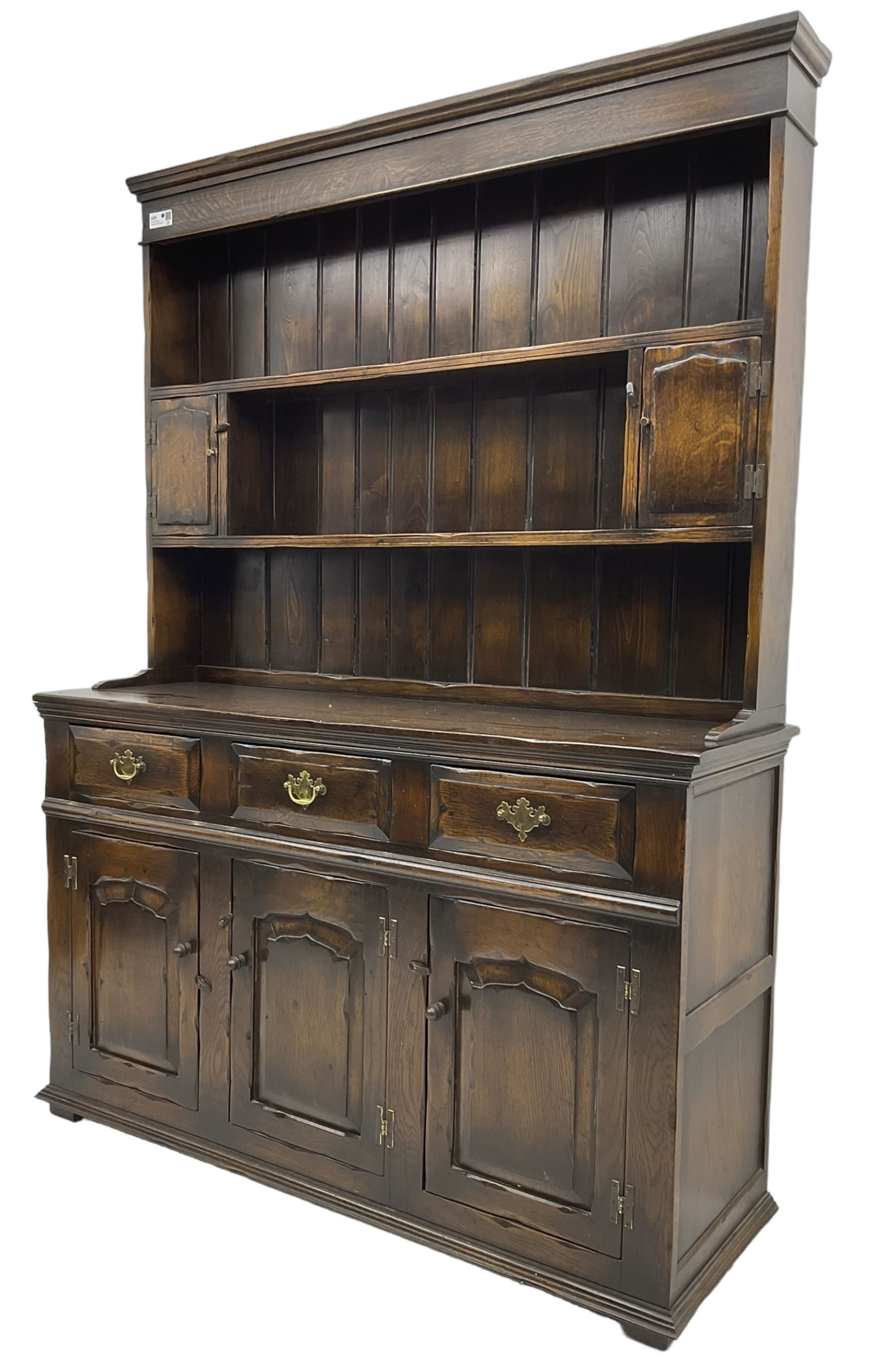Georgian design oak dresser, the two-tier plate rack with two flanking spice cupboards, the base fitted with three drawers over three arched fielded panelled cupboards, lower moulded edge on block feet