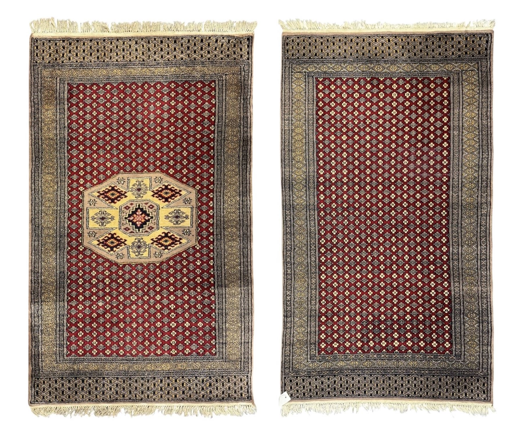 Pakistani Kashan hand-knotted rug with a central medallion and intricate geometric floral patterns, set against a red field and framed by a multi-band border (156 x 94cm); Pakistani Kashan rug with a repeating floral motif across the red field, enclosed by a detailed geometric border in complementary tones (162 x 95cm)