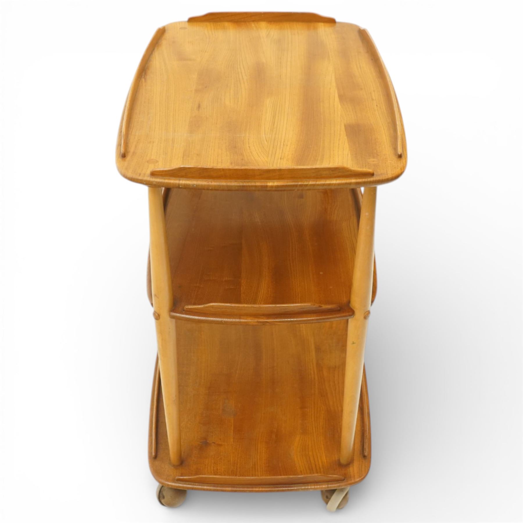Ercol - elm tea trolley, Model 458. Rectangular three-tier form with shaped gallery edges, supported on turned upright supports, raised on castors