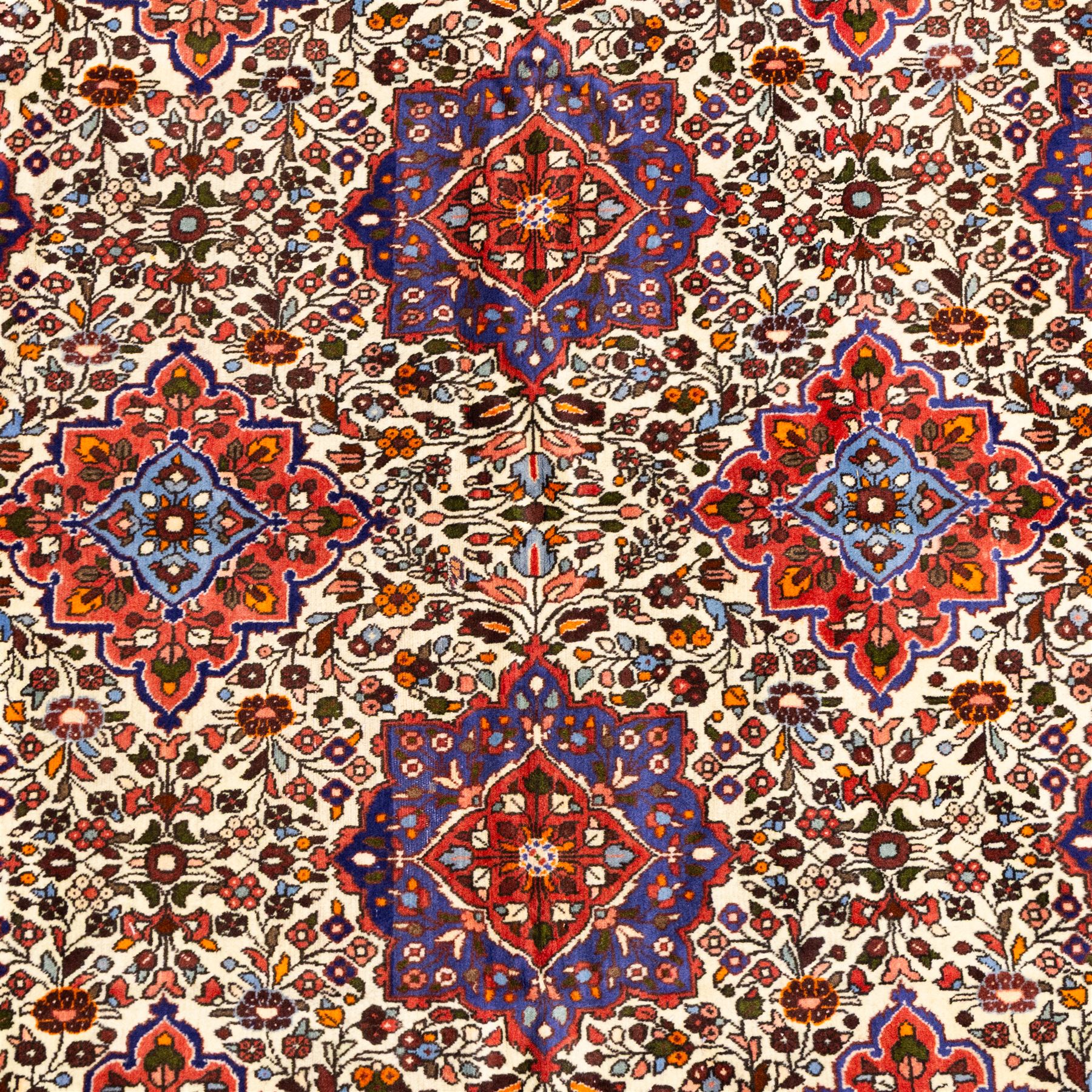 West Persian Hamadan hand-knotted rug, ivory field decorated with a repeating lattice of stylised geometric medallions interspersed with small floral motifs and angular vine ornament enclosed by a sky blue border of stylized rosettes and geometric devices between multiple guard stripes, with cotton fringe ends  