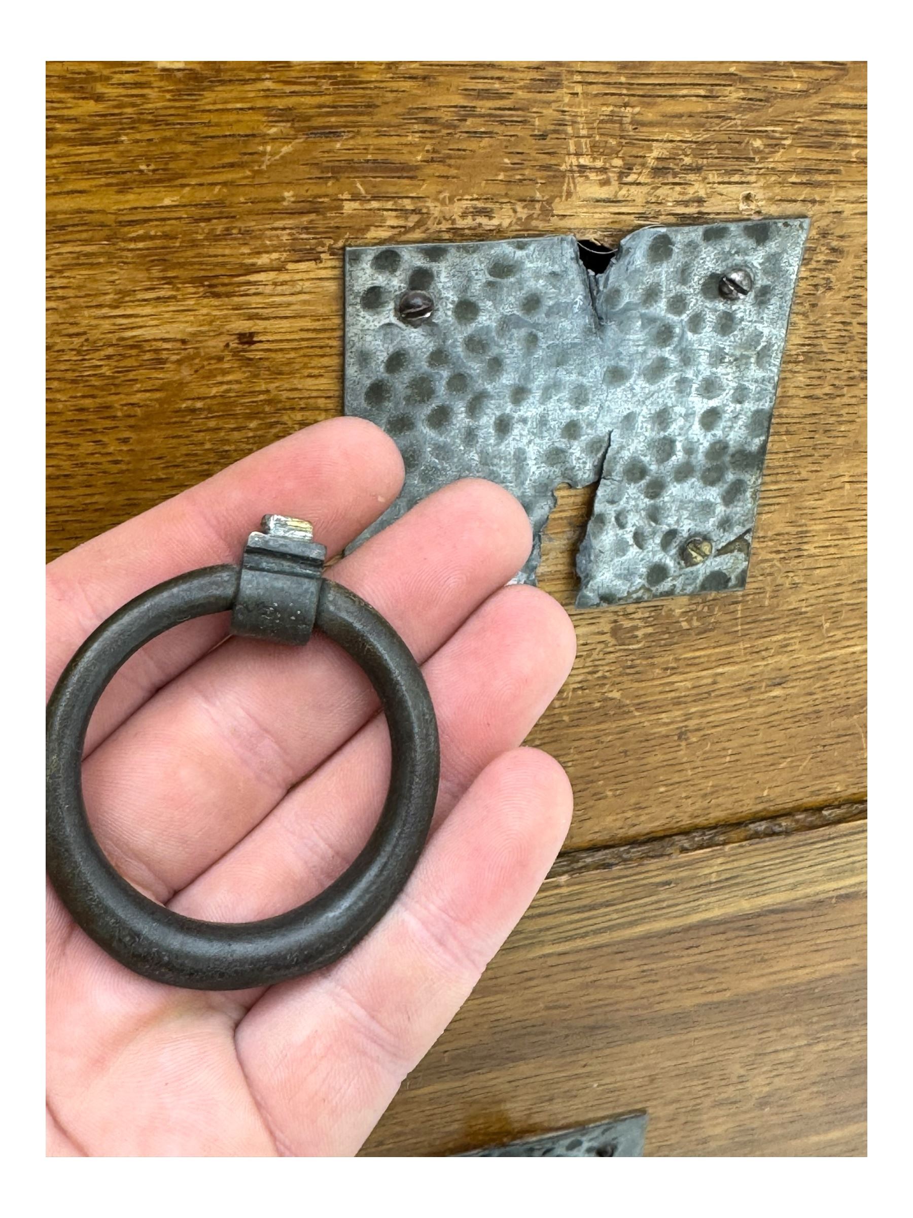 Early 20th century Arts and Crafts oak dressing chest, the arched mirror flanked by floral marquetry inlaid uprights above a shelf and drawer, over three long drawers with square hammered metal plates and circular pulls, on slender supports with castors