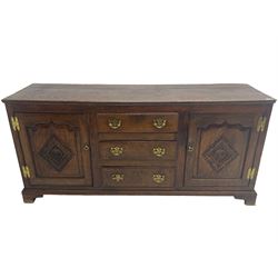 George III oak dresser base, fitted with three graduating central drawers, flanked by two arched fielded panel doors, the facias carved with a lozenge with central rosette, lower moulded rail over bracket feet
