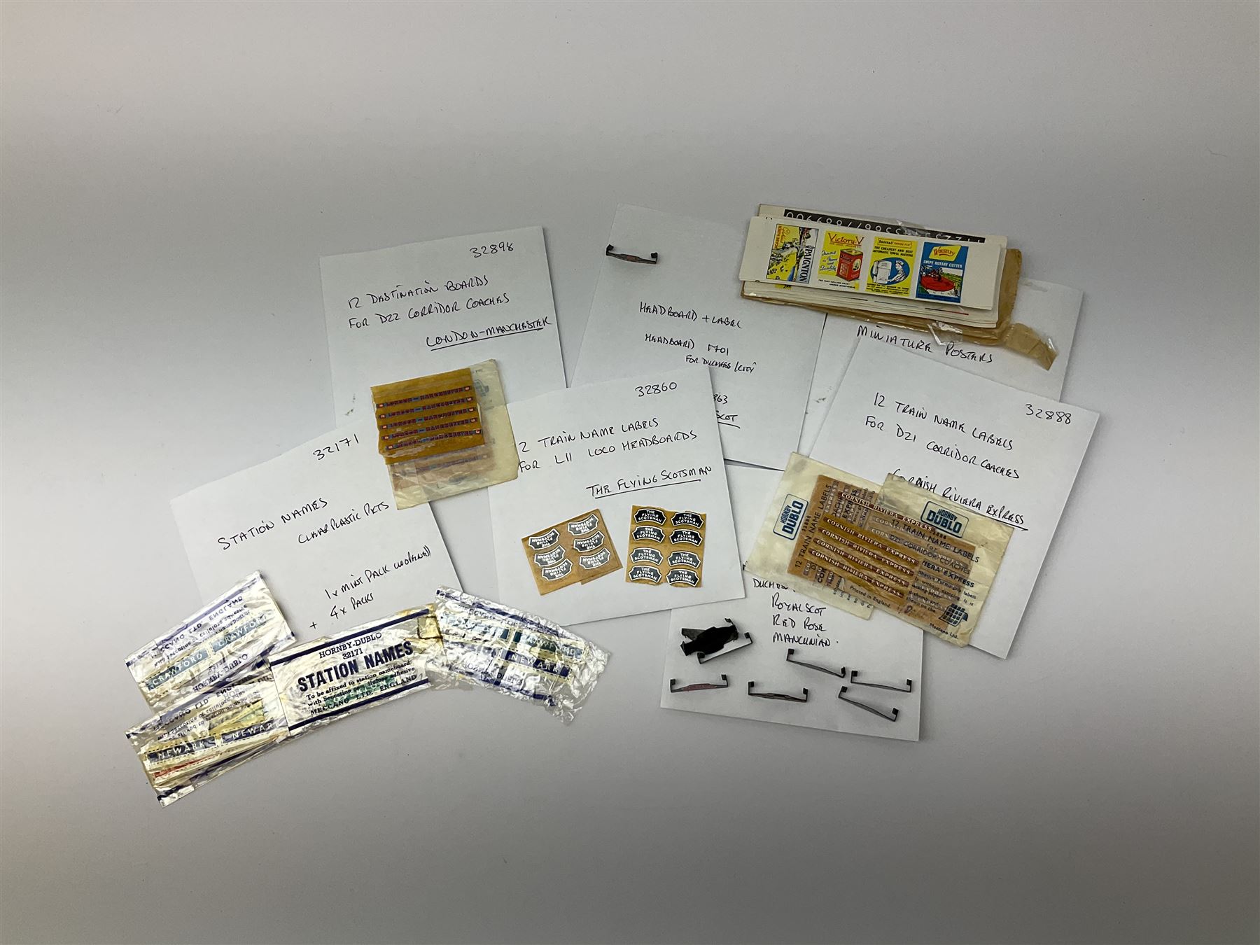 Hornby Dublo etc - large quantity of labels etc comprising headboards and train names including Mallard, Mancunian, Bristolian, Royal Scot, Flying Scotsman, Red Rose, White Rose, etc; destination boards for corridor coaches; station names; miniature posters; insulating tabs; lubricating oil etc; many in original packets.