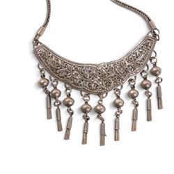 Collection of Middle Eastern jewellery, including silver necklace with a crescent  shaped pendent with beadwork and barrel tasselled ends, nickel silver wedding necklace with filigree decoration, coin bracelet, two bridal wedding caps and two others 