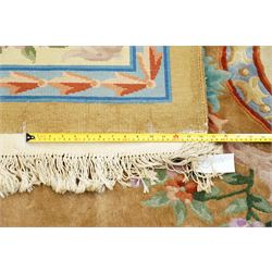 Chinese Aubusson/Savonnerie style hand-knotted carpet, ivory field with a central oval medallion issuing with stylized bouquets in shades of blush pink, pale blue, sage and green, enclosed by ribbon-tied floral garlands and conforming borders within narrow guard stripes, with cotton fringe ends 