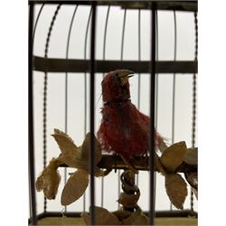 Late 19th/early 20th century birdcage automaton, the single bird adorned with bright red feathers seated upon T-bar perch with a small gathering of faux vines and foliage under a rectangular cage with single loop carry handle, raised upon gesso base housing the movement with a lever to the side, H28cm