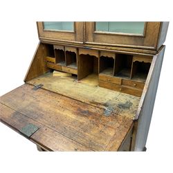 George III oak bookcase on bureau, the double arched top enclosed by two shaped glazed doors, fall-front concealing fitted interior, over four graduating cock-beaded drawers, on bracket feet