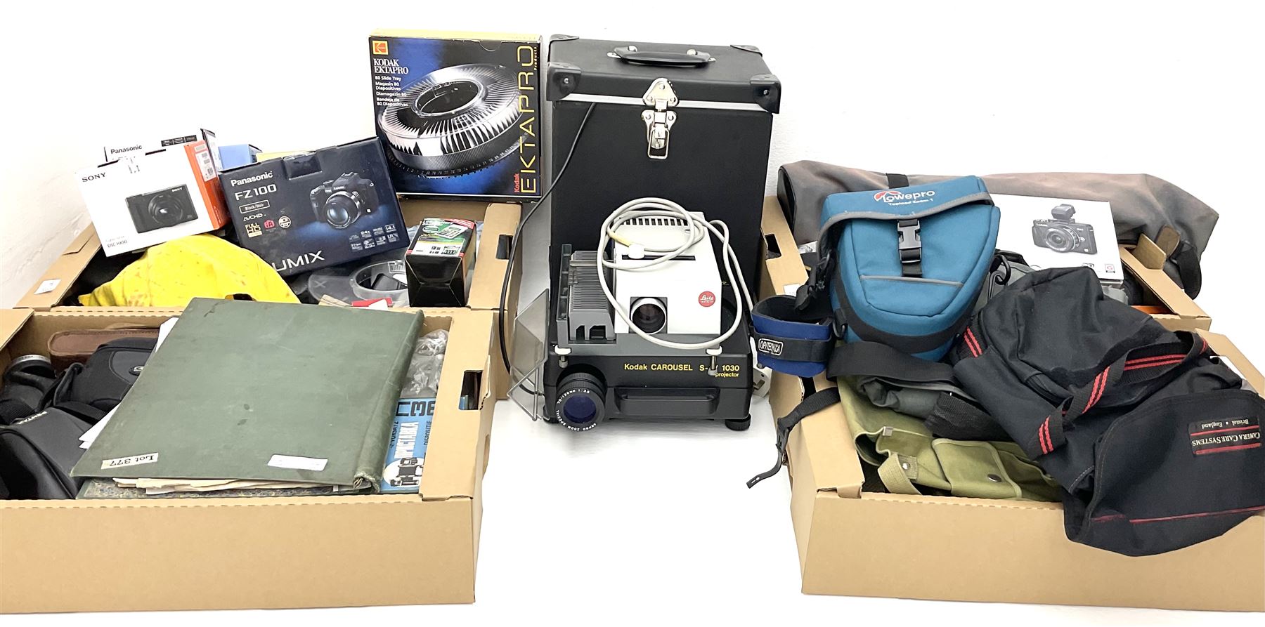 Large quantity of camera equipment in three boxes - Lumix GX1 camera, Canon EOS 500 camera, Lumix FZ100 camera, Pantax  MZ5n, various other cameras, Swift spotting Scope 20 x 60 in box,  Maxtor hard drive, three tripods, Kodak carousel projector, Pradolux slide projector, a selection of camera bags and other camera equipment. 