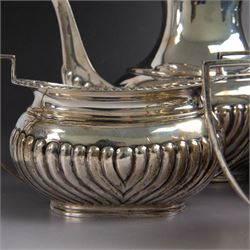 Edwardian silver four piece tea service, comprising coffee pot, teapot, twin handled open sucrier and milk jug, all of oval bellied form, part fluted and with oblique gadrooned rim, with Bakelite type handles and finials to teapot and coffee pot, hallmarked Fordham & Faulkner, Sheffield 1913